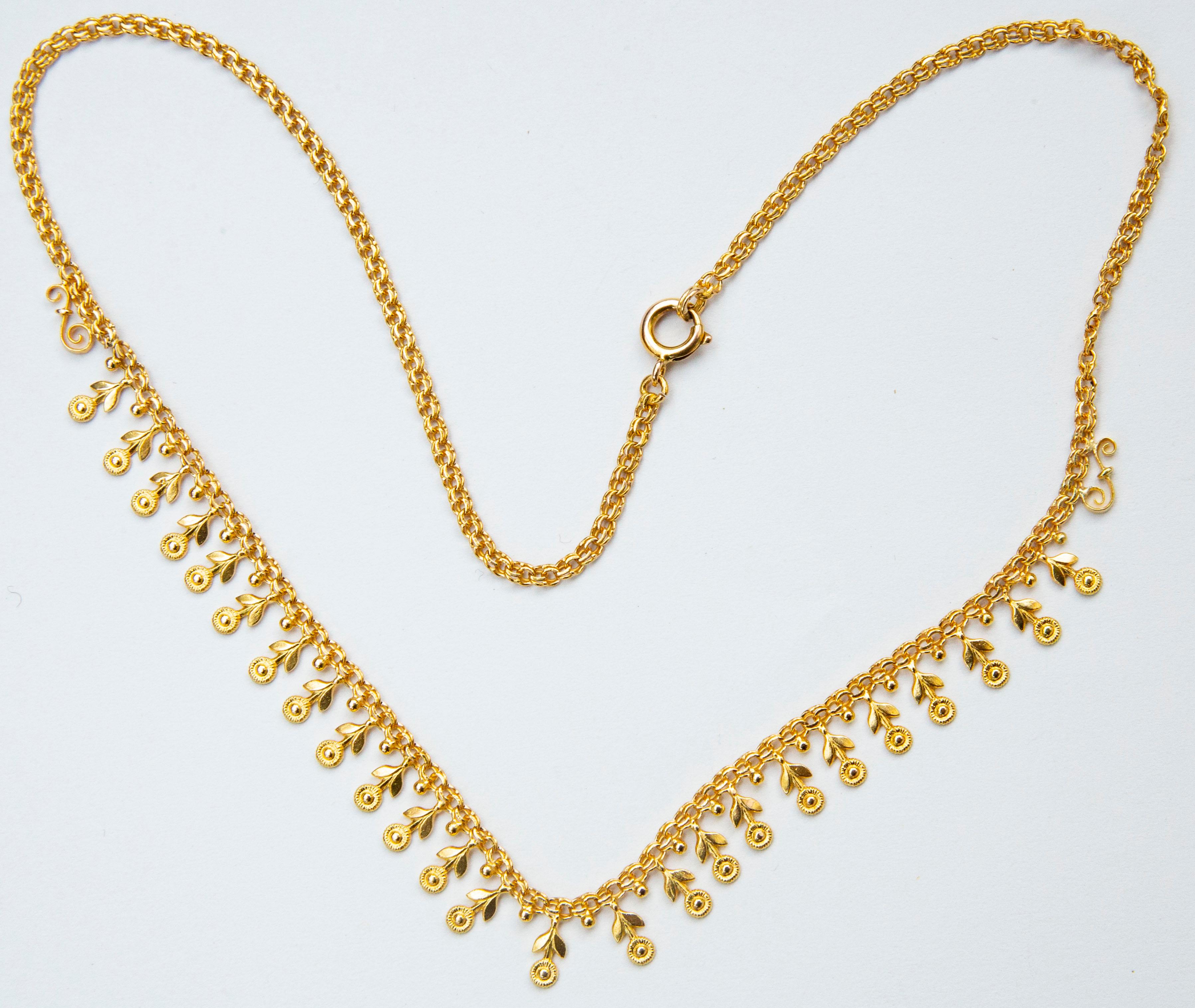A vintage (1950s) 14 karat solid yellow gold choker necklace decorated with flower and ball - shaped charms. The necklace features a double rope chain that closes with a spring ring clasp. The necklace has a very cheerful appearance and would be a