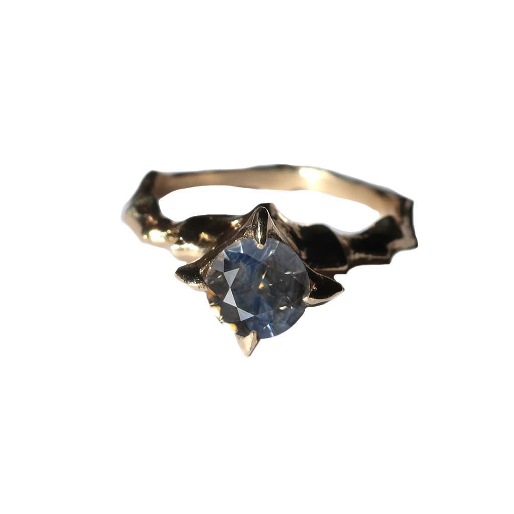 This beautiful ring is handcrafted in 14k yellow gold and set with this unique bi-color sapphire. Strewn with hues of light blue and amber, this stone mesmerizes as it changes colors in the light. 

Please note this piece is made to order in your