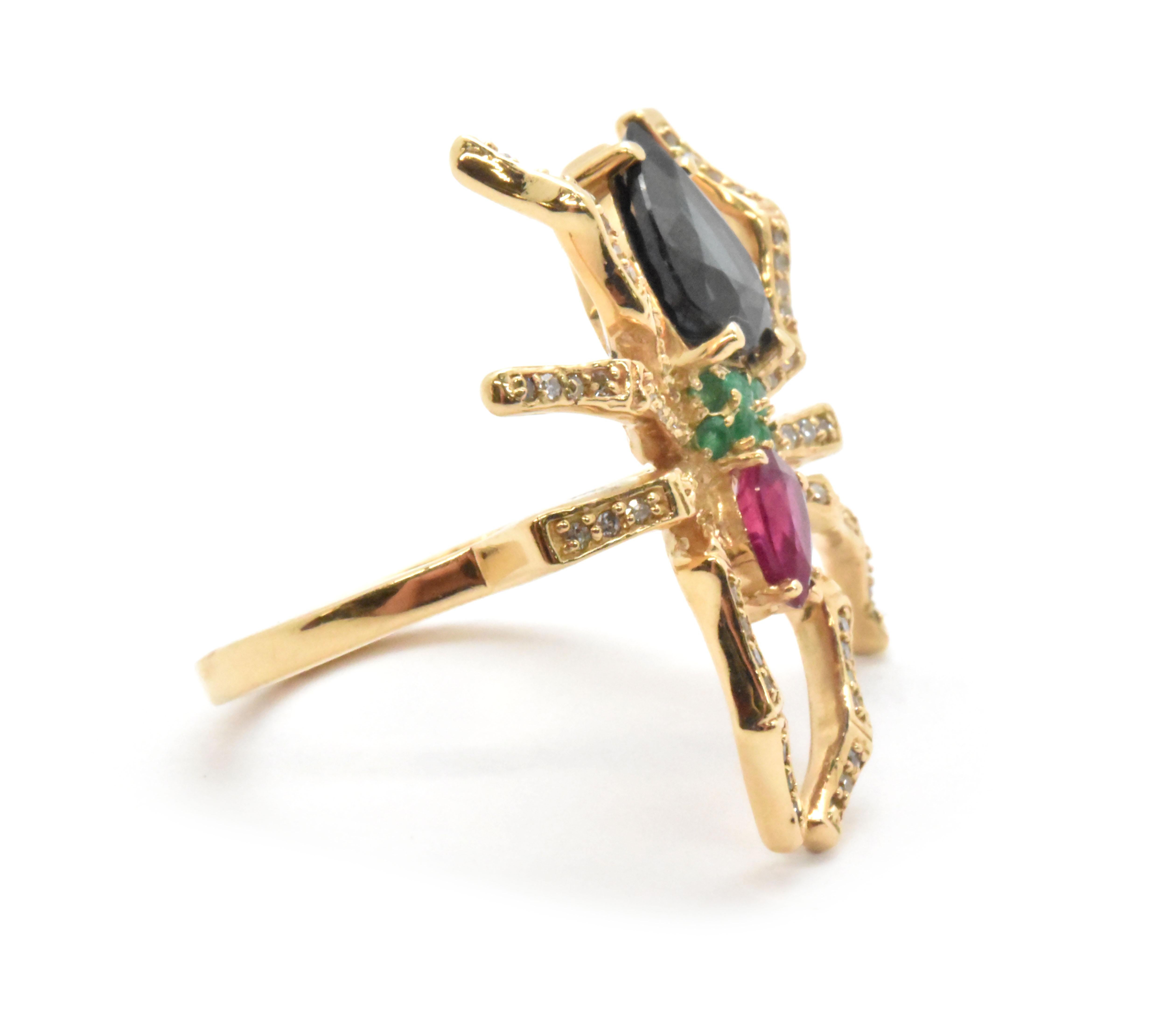 This one-of-a-kind, 14k yellow gold spider ring features a sapphire, ruby and emerald stone body, with diamond legs. The ruby stone weighs 0.60ct. The six emerald stones have a total weight of 0.25ct. The sapphire stone weighs 2.40 carats. Lastly,