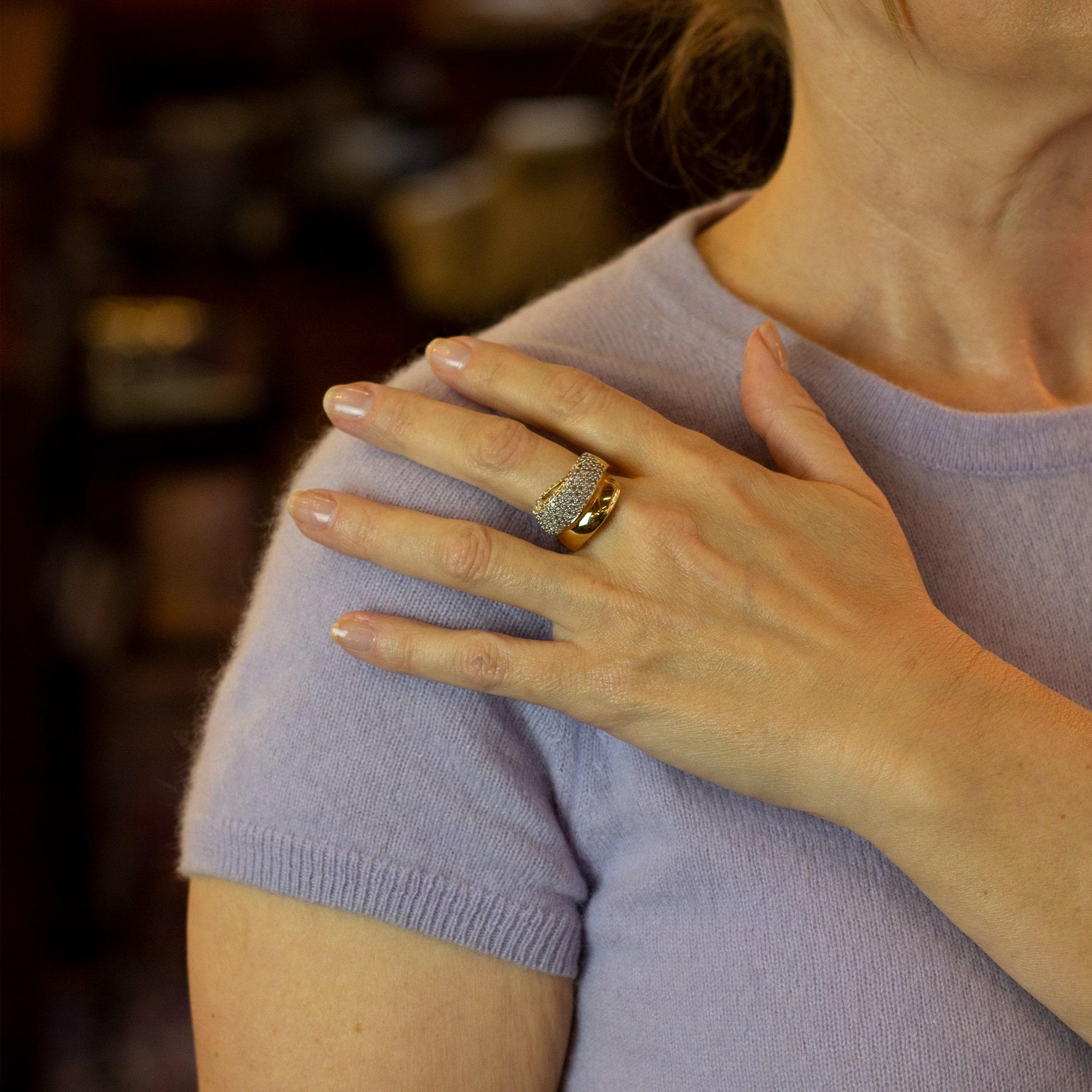 A bold 14 karat yellow gold dress or cocktail ring with pave set single cut diamonds. The 'swirl' style ring appears to be a single bar of gold that twists up and loops over the top of the finger. The top section of this 'swirl' is set with 105 0.01