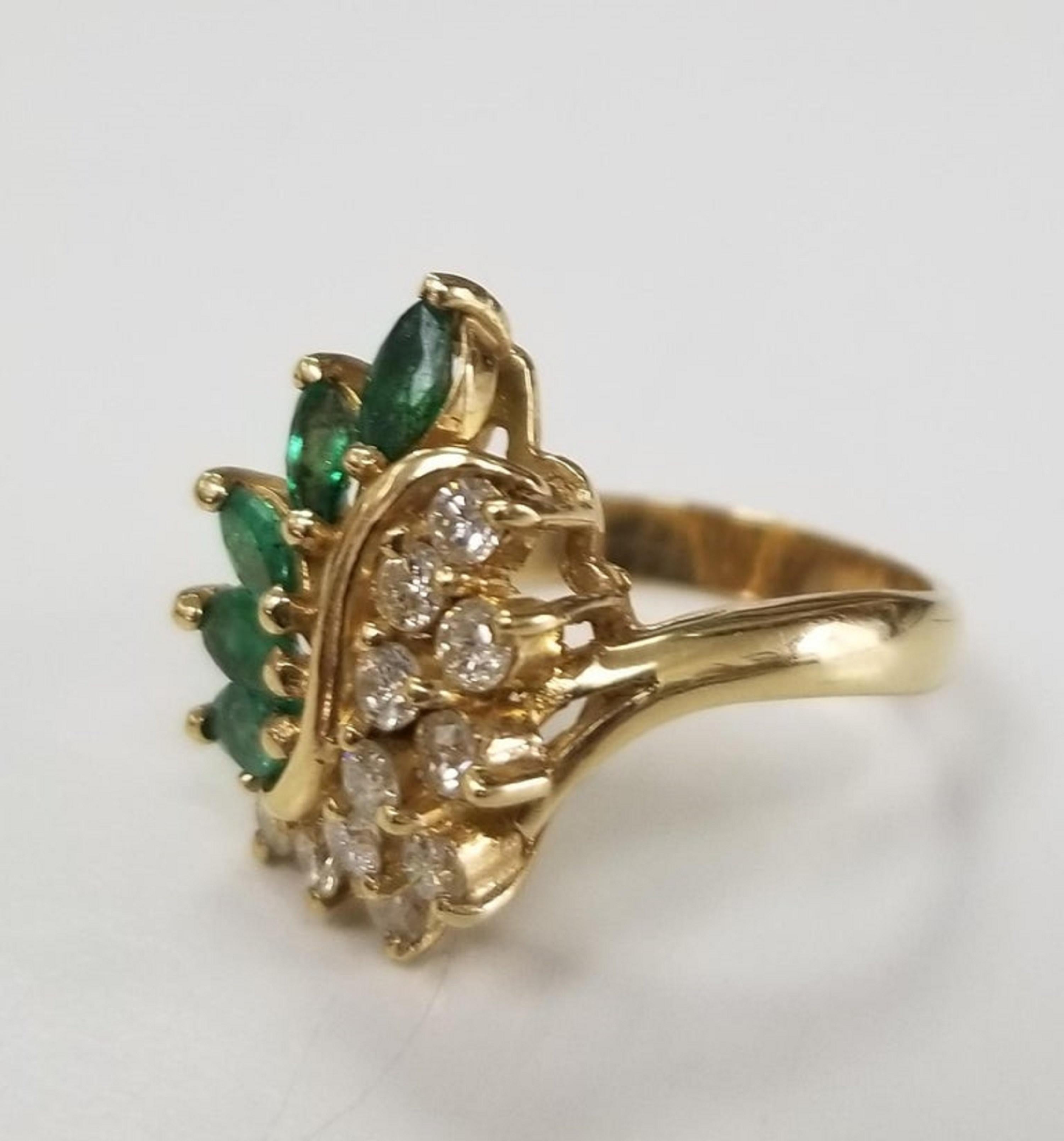 14k yellow gold emerald and diamond ring, containing 11 round  emerald weighing .65pts. and 5 marquise cut emeralds weighing .65pts.  This ring is a size 5.5 but we will size to fit for free.