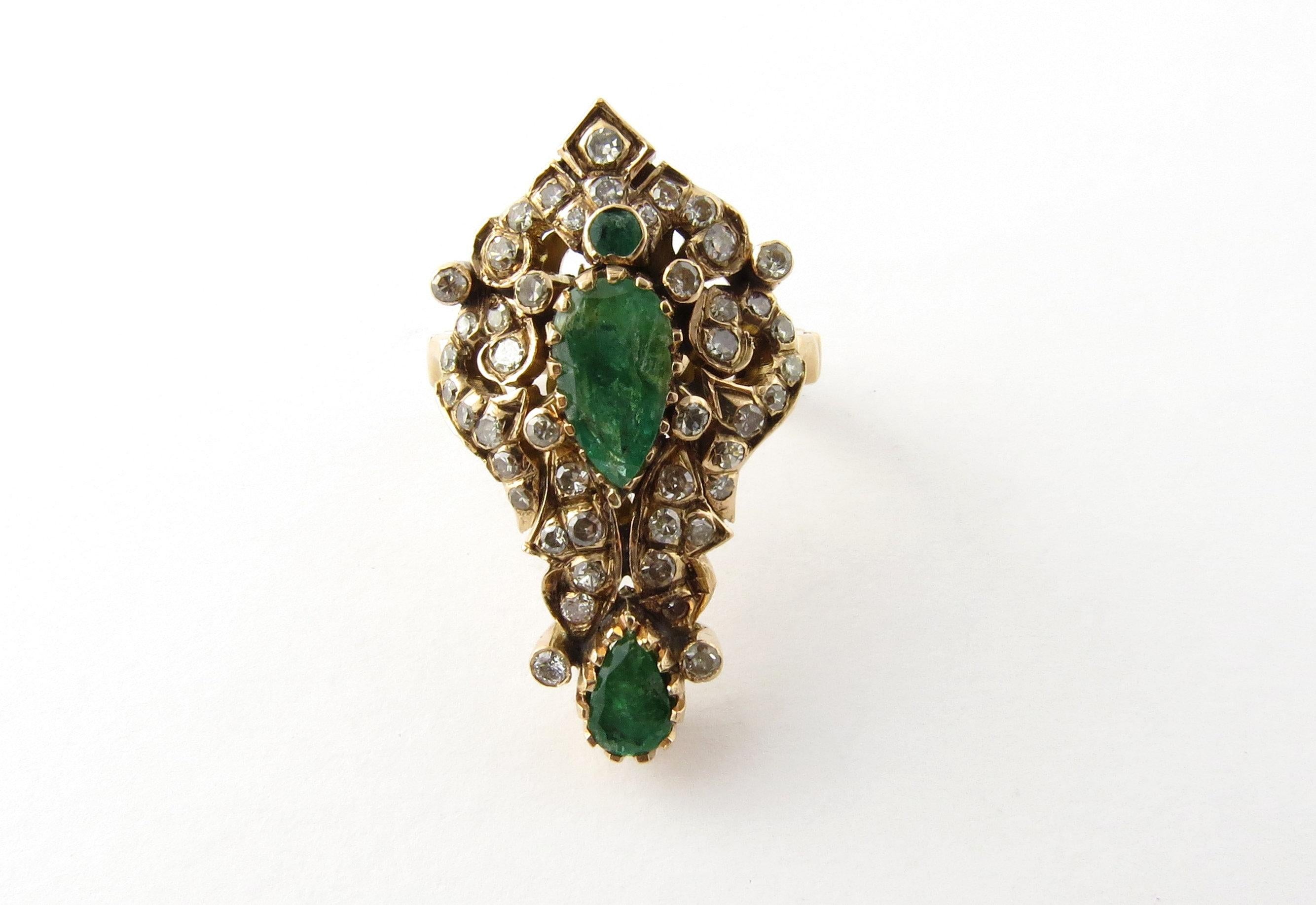 Vintage 14 Karat Yellow Gold Natural Emerald and Diamond Ring Size 6.75-

This spectacular ring features three genuine emeralds (two pear, one round) and 46 round single and brilliant cut diamonds set in ornate 14K yellow gold.  

Top of ring