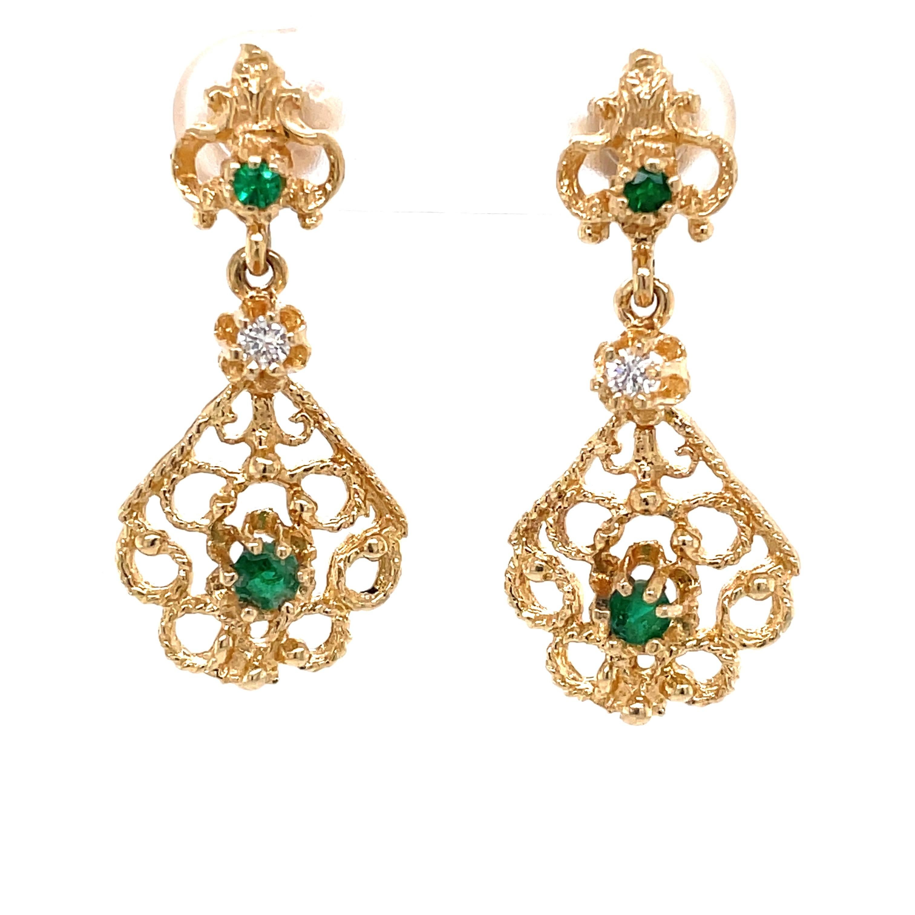 Emerald and diamond accents dress up this regal pair of fourteen karat 14k yellow gold drop earrings. Four round faceted emeralds, two .05 carat and two .01 carat plus two .02 carat H/VS diamonds
adorn the elegant gold filigree of this Victorian