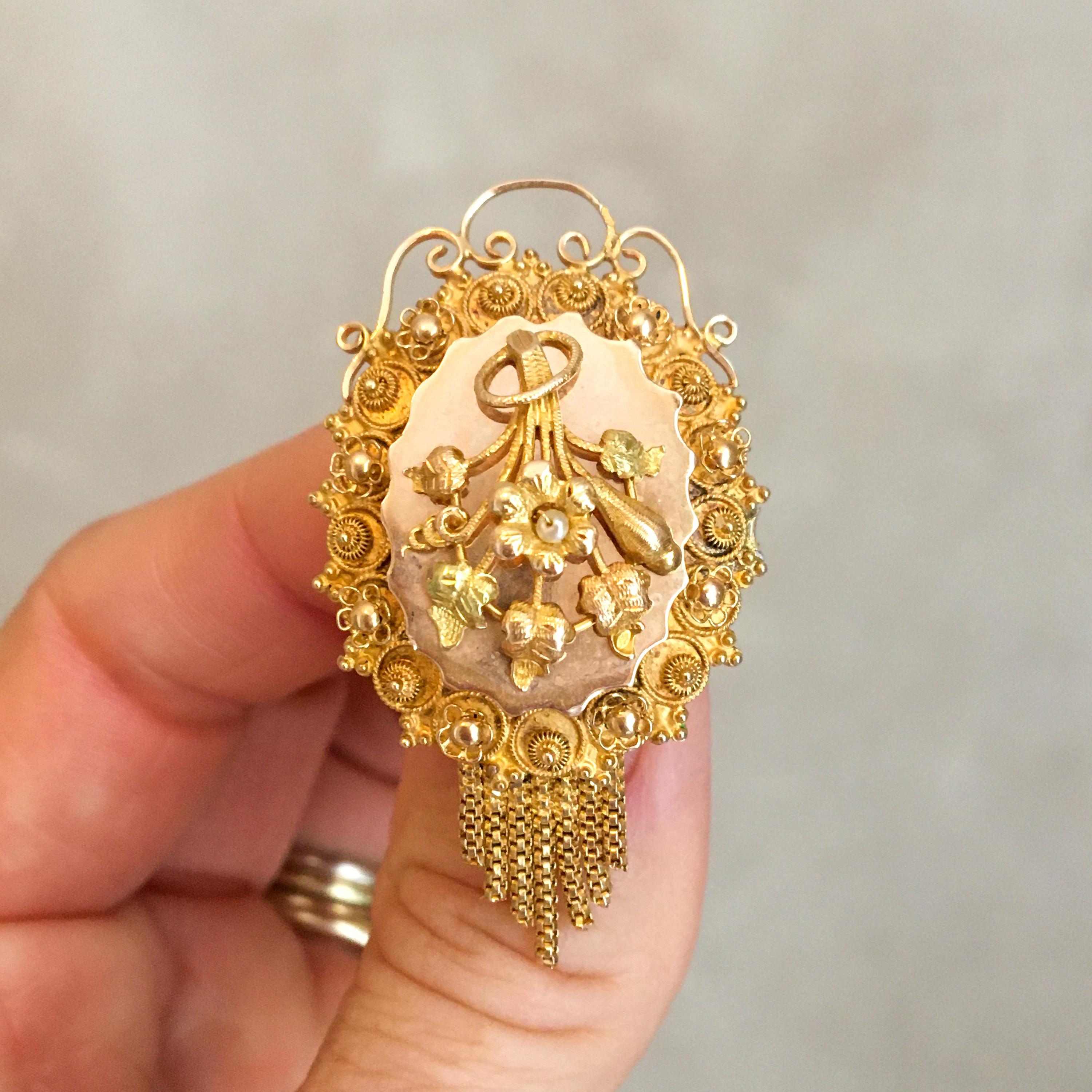 An antique 19th century 14 karat yellow gold brooch set with cannetille work and an Orient pearl. The center of the brooch is created with a floral design with leaves, a flower and an Orient pearl on top. The border of the frame is made of fine