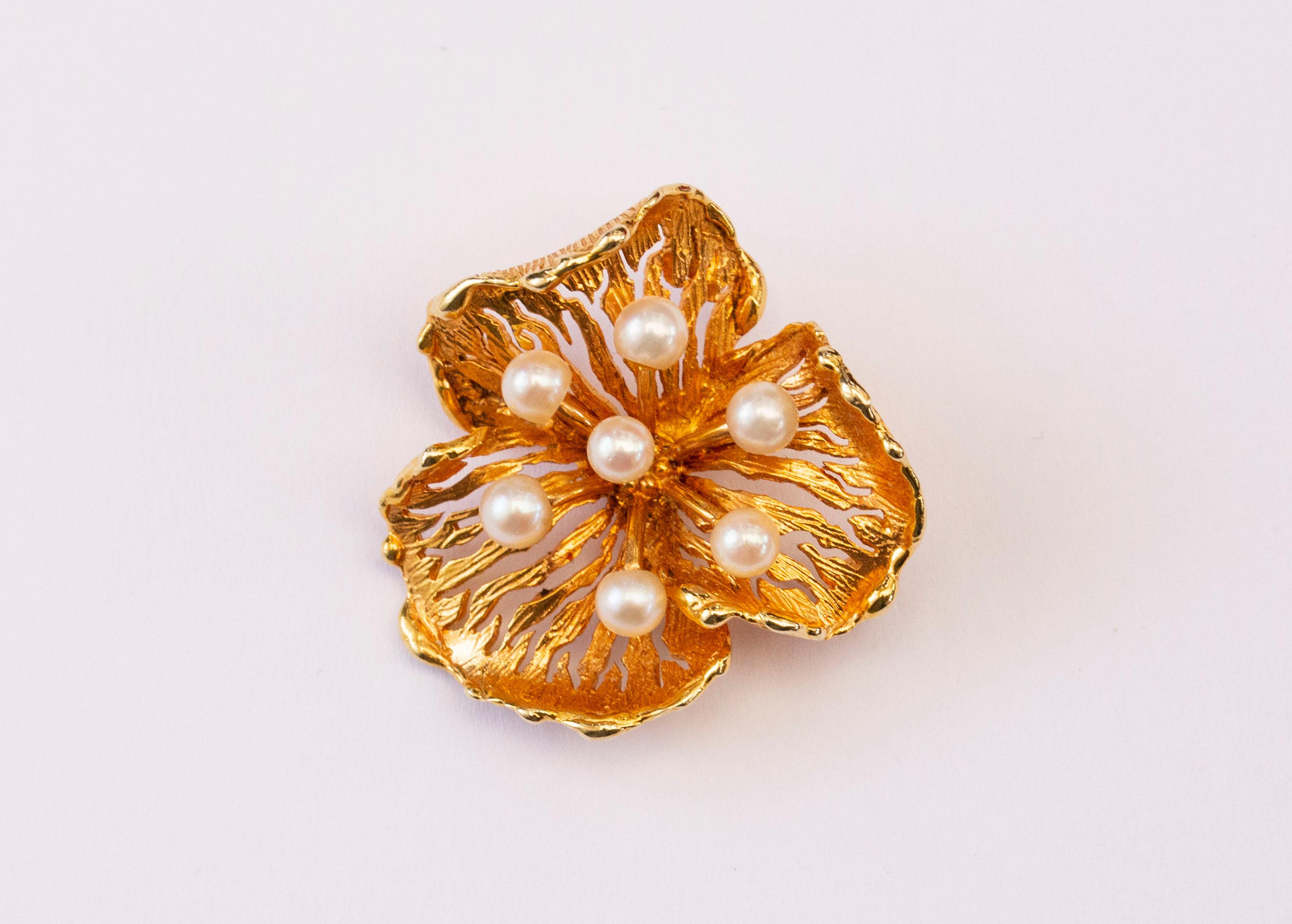 A vintage 14 karat yellow gold brooch in a form of an abstract  flower with seven cream-colored cultivated Akoya pearls in the middle. The brooch is of high quality and it features a precise and intricate finish. The brooch could be a great asset