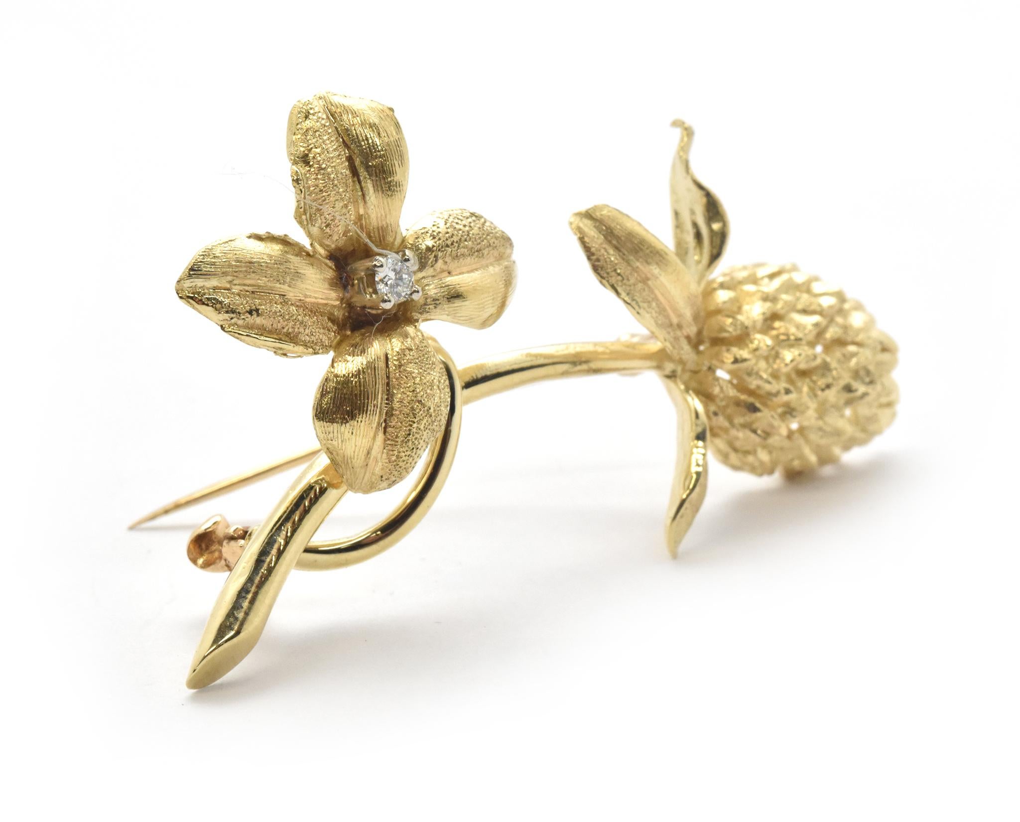 This vintage pin features natural floral designs and aspects designed in 14k yellow gold. One element of the pin is a four-petal flower with a 0.05ct diamond accented center. The balancing element at the end of this pin is a thistle-like floral