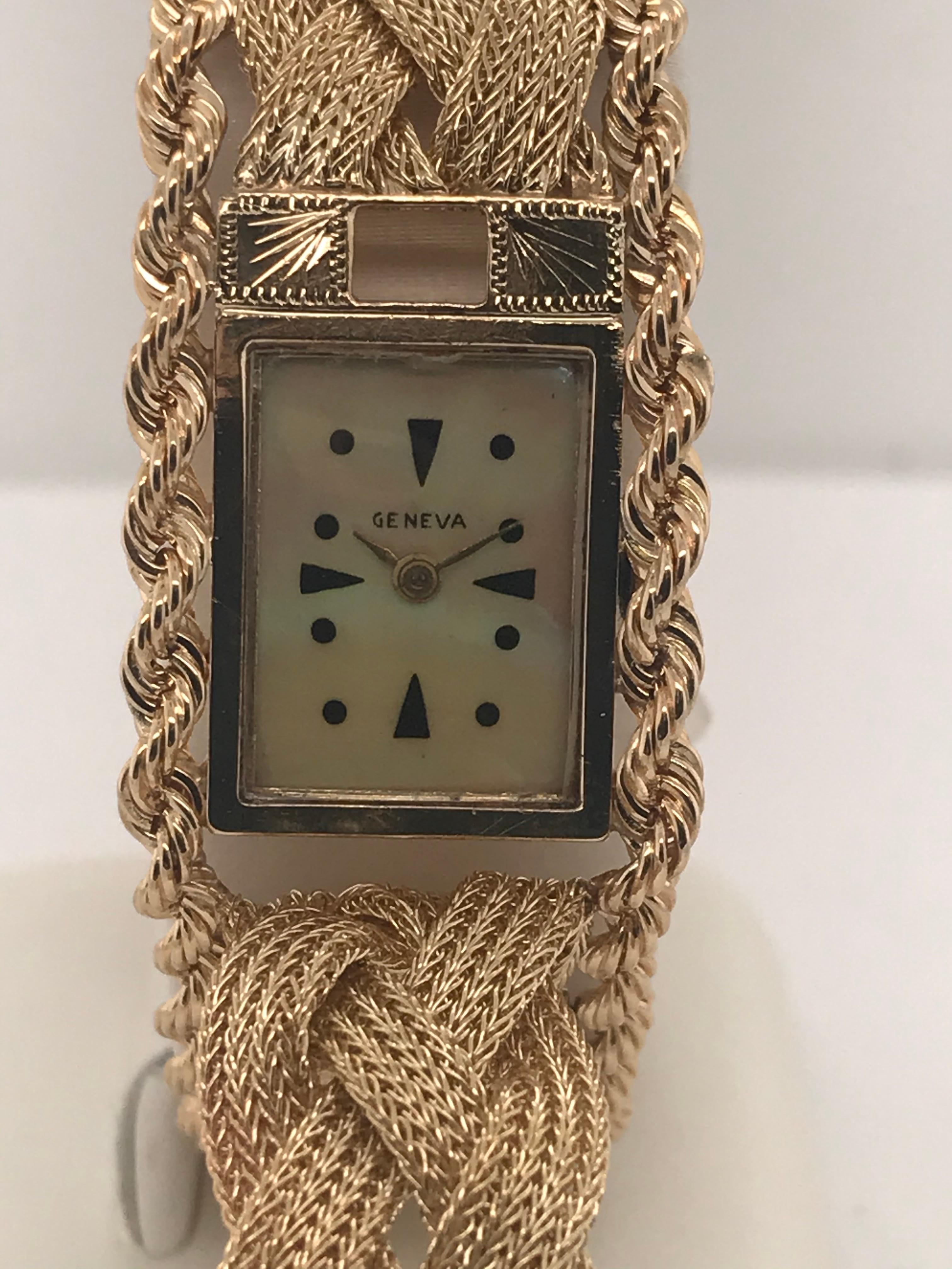 Ladies 14 karat yellow gold cover watch by Geneva.  This one of a kind  watch has 7 single cut diamonds and  7 round bright green chalcedony stones.  It has mother of pearl dial, safety chain for security, and a braided rope chain style bracelet. 