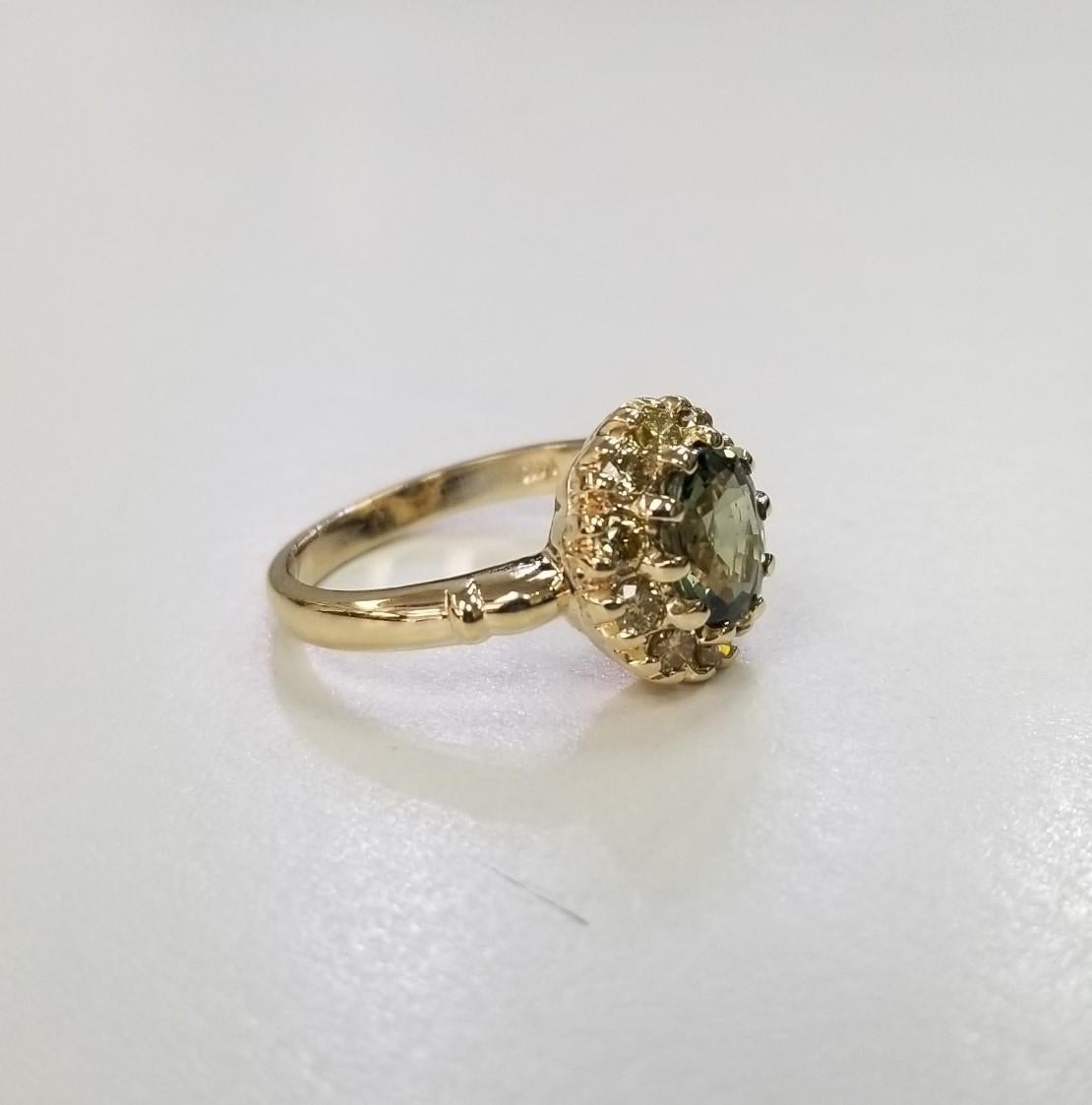 14 karat yellow gold Green Sapphire yellow diamond halo ring, containing 1 oval green sapphire of gem quality weighing 1.54cts.  and 10 round full cut yellow diamonds of very fine quality weighing .55pts.  This ring is a size 7 but we will size to