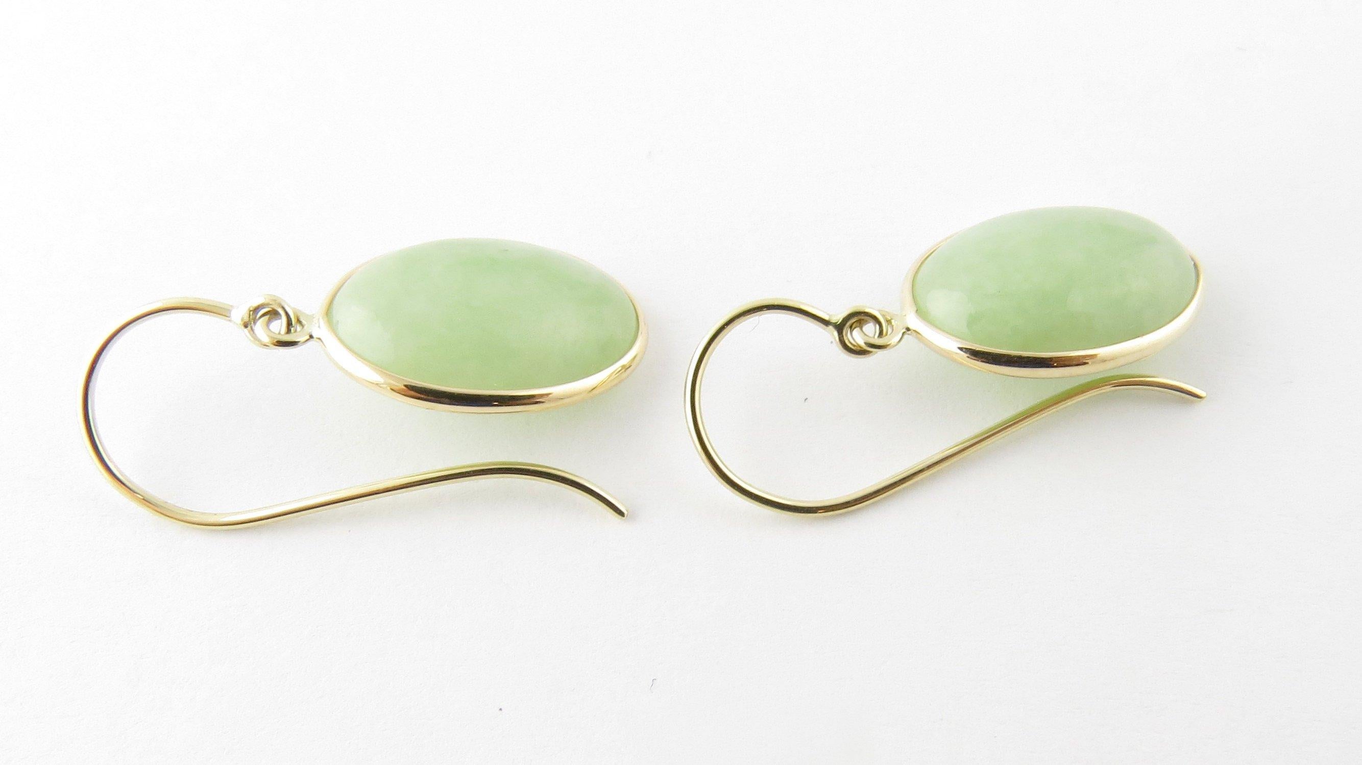 Vintage 14 Karat Yellow Gold Jade Earrings- 
These lovely dangling earrings each feature one oval jade stone (15 mm x 11 mm) set in classic 14K yellow gold. French wire closures. 
Size: 25 mm x 11 mm 
Weight: 1.8 dwt. / 2.8 gr. 
Hallmark: Acid
