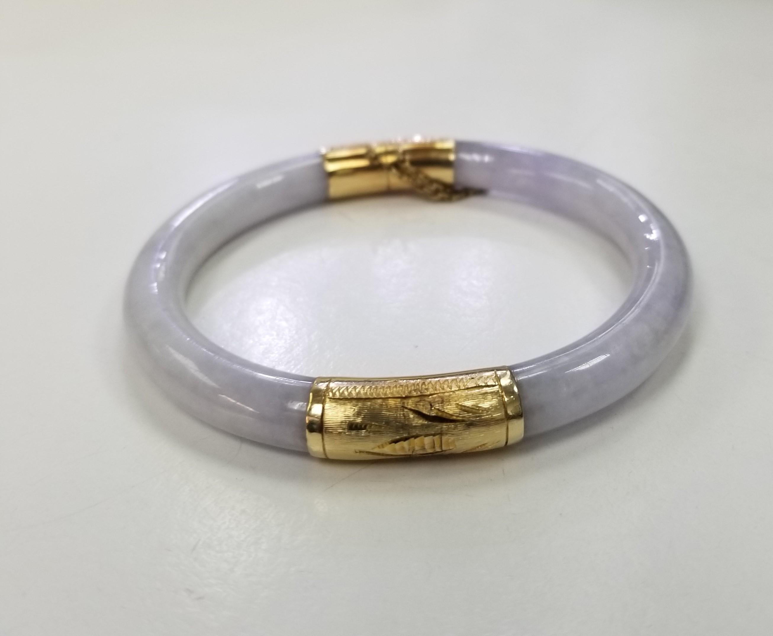 A 14 karat yellow gold lavender jade hinged bangle bracelet. This carved lavender jade bangle has floral engraved gold end caps with a hinge at one end and a clasp at the other.
Width: 7.25 mm
28 Grams
* Please note that this is a vintage item and