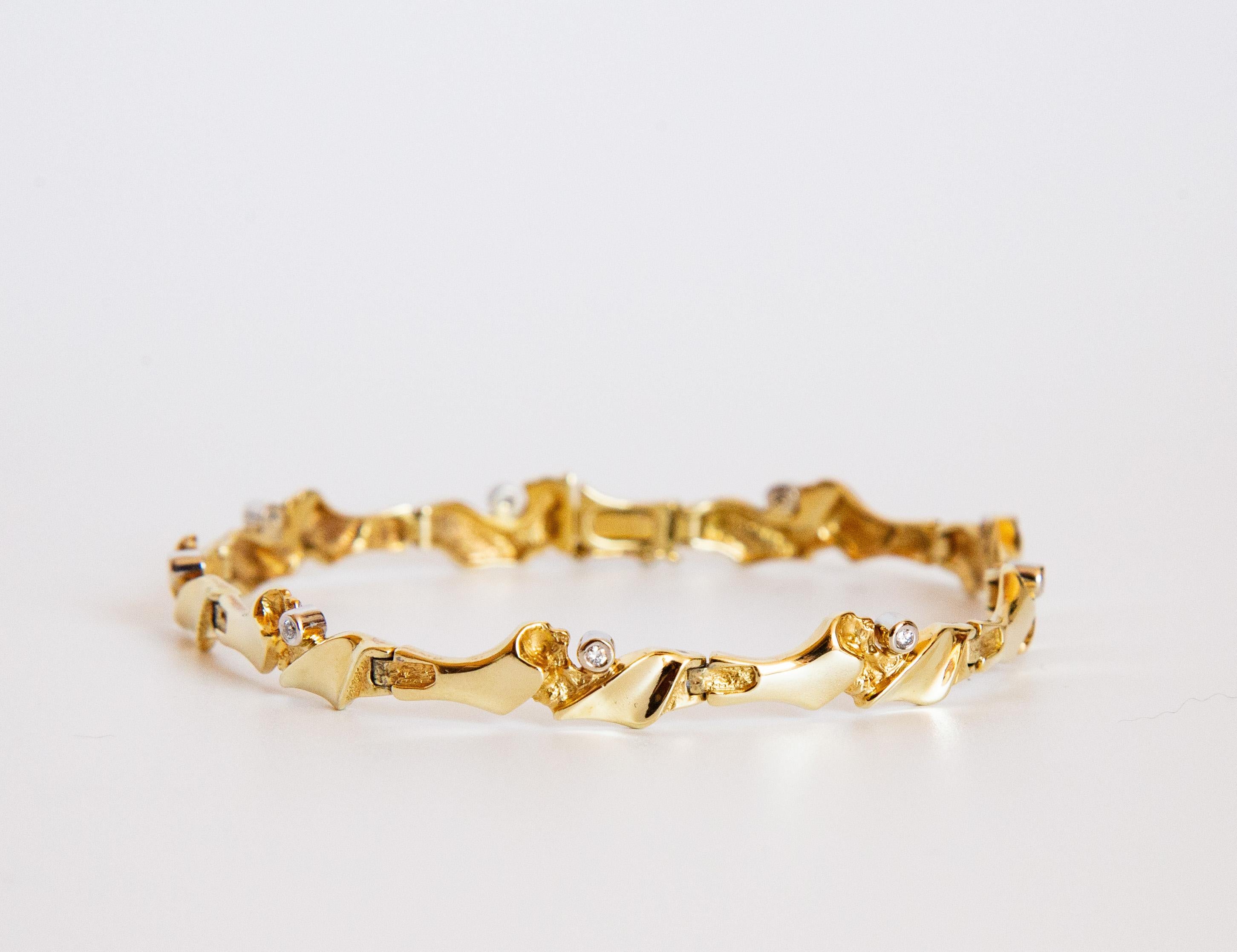 Una pulsera Link de oro amarillo de 14 quilates con diamantes. En  La pulsera tiene eslabones de forma asimétrica, con un acabado parcialmente mate. La pulsera está engastada con 9 diamantes talla brillante de aprox. 0,09 ct en total (9x aprox. 0,01