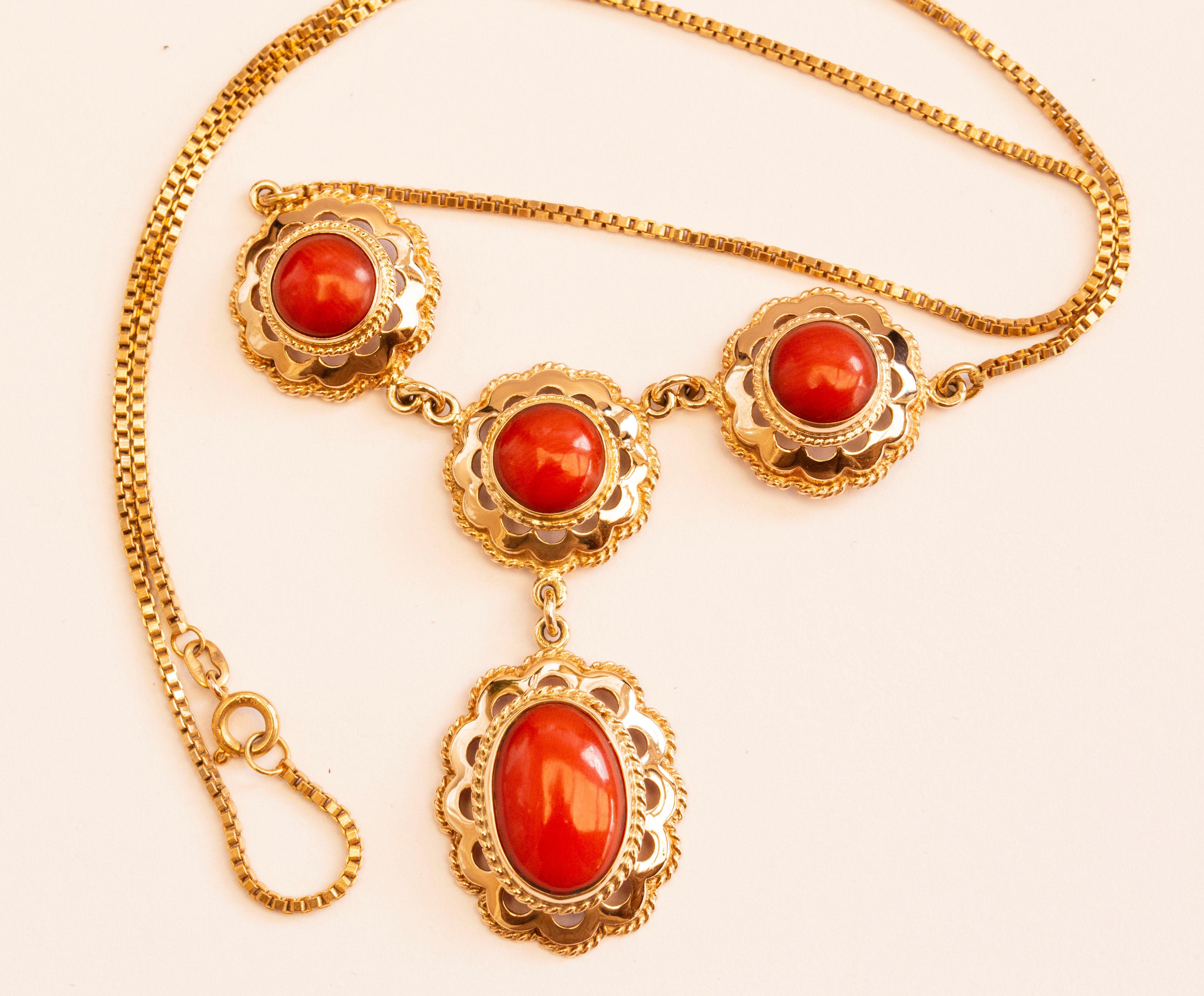 A vintage 14 karat yellow gold necklace with a gold ornament set with genuine red coral cabochons. The ornament consists of three connected gold flower-shaped links with cabochon-cut round red coral, of which one is linked with an oval red coral set