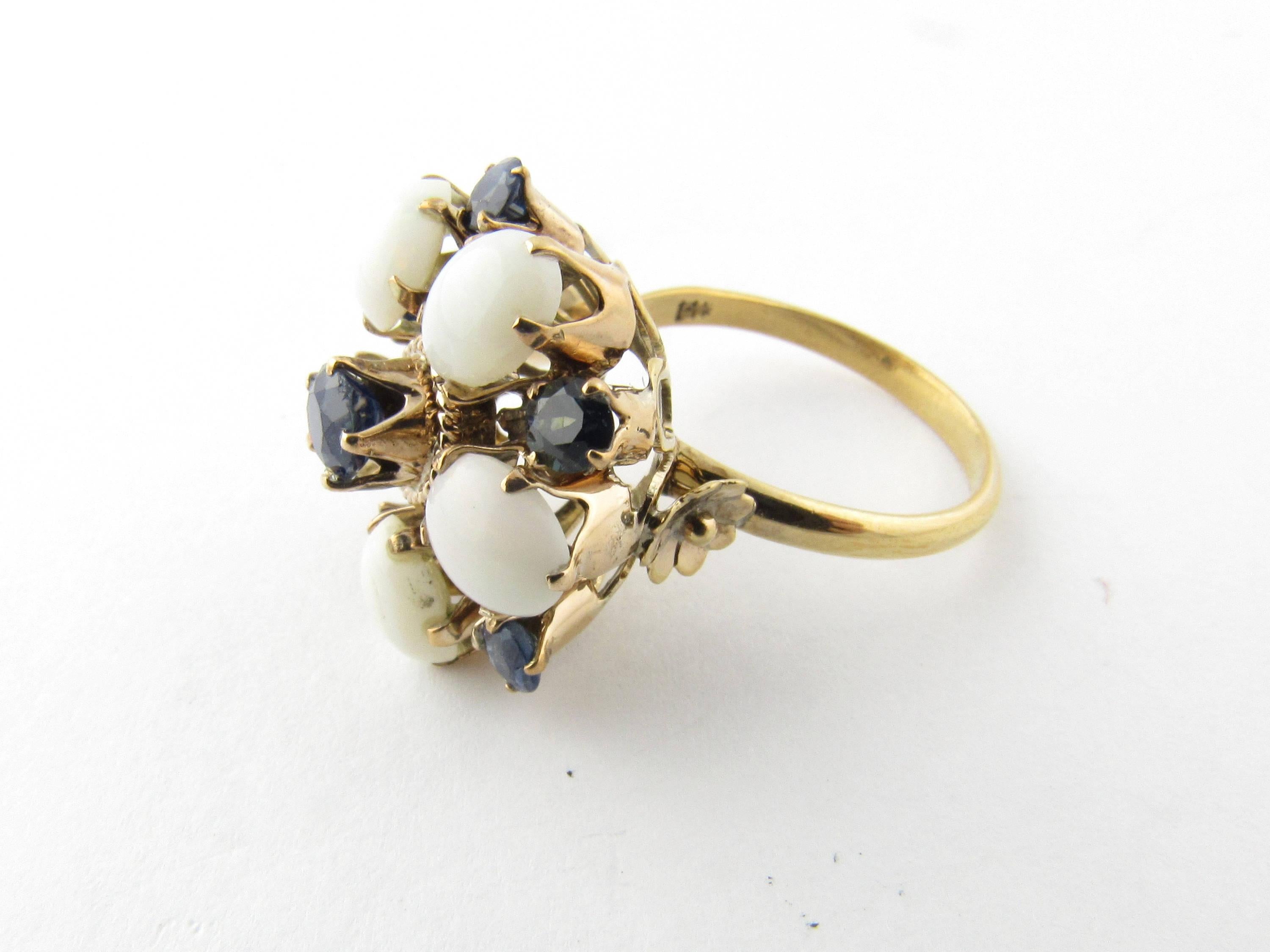 Vintage 14K Yellow Gold Opal and Sapphire Flower Ring. 
Artfully high set sapphire and opal flower petals in 14K yellow prongs. Center sapphire has a milgraine lower border while a gold flower adorns each side of the base at shank. 
Size 6 1/4 Shank