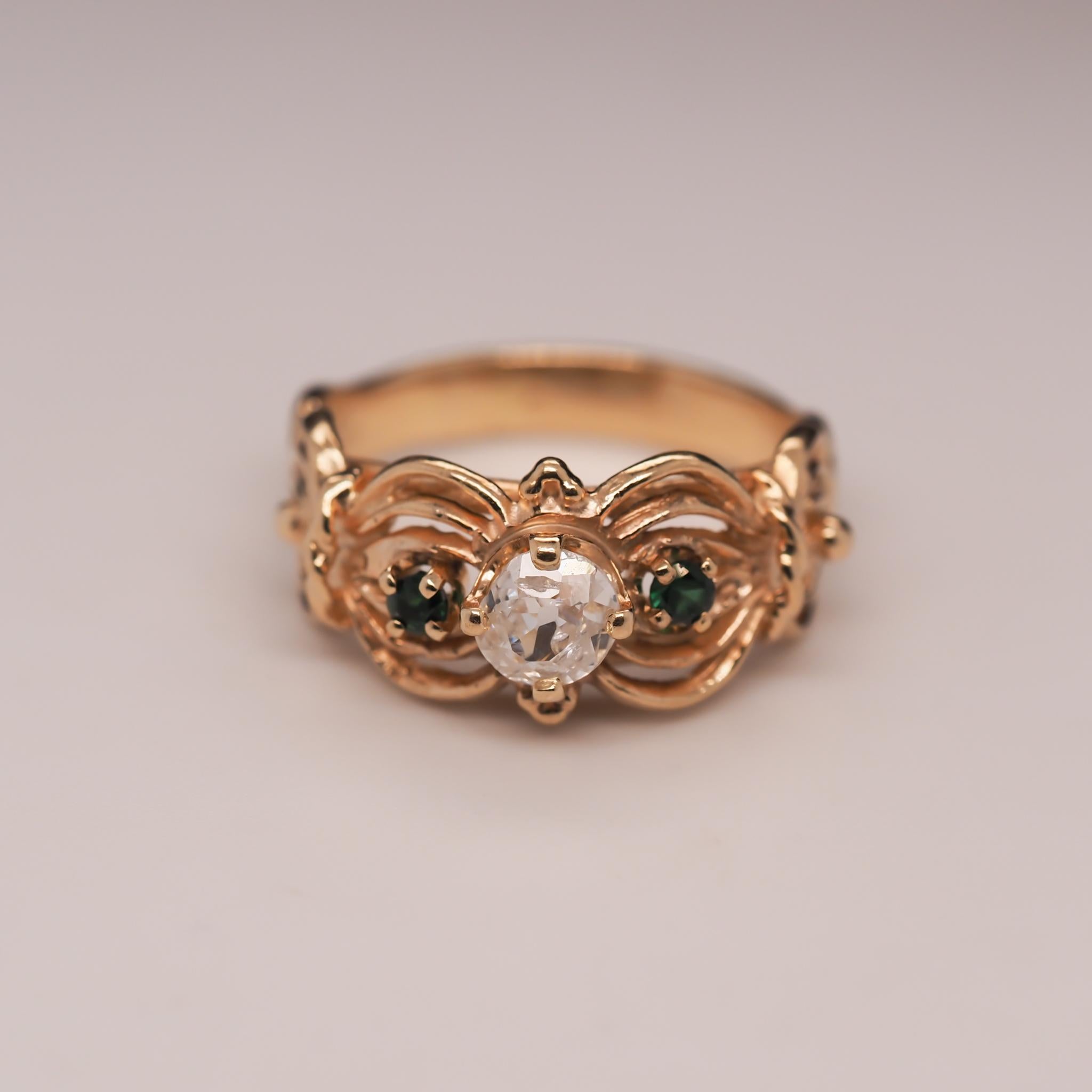 Year: 1960s

Item Details:
Ring Size: 8.75
Metal Type: 14K Yellow Gold [Hallmarked, and Tested]
Weight: 5.7 grams

Diamond Details: .50ct, Natural Diamond, Old Miner brilliant, F color, SI Clarity

Side Stone Details: Emeralds, Natural, Round,