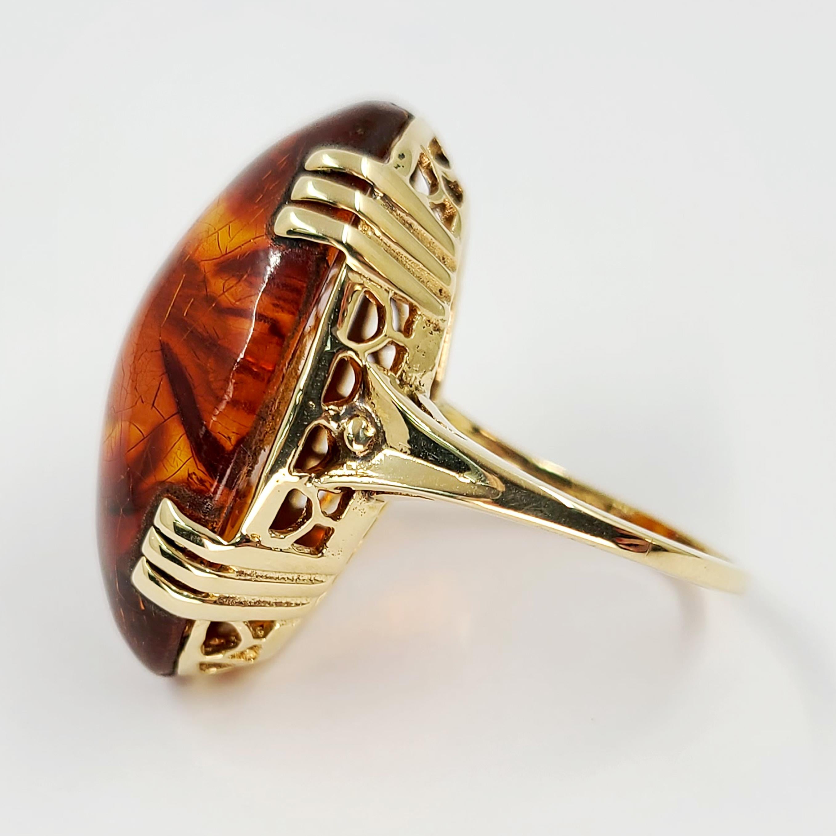 14 Karat Yellow Gold Cocktail Ring Featuring A 29mm x 18mm Oval Cabochon Amber. Current Finger Size Is 8; Purchase Includes One Sizing. Finished Weight is 7.9 Grams.