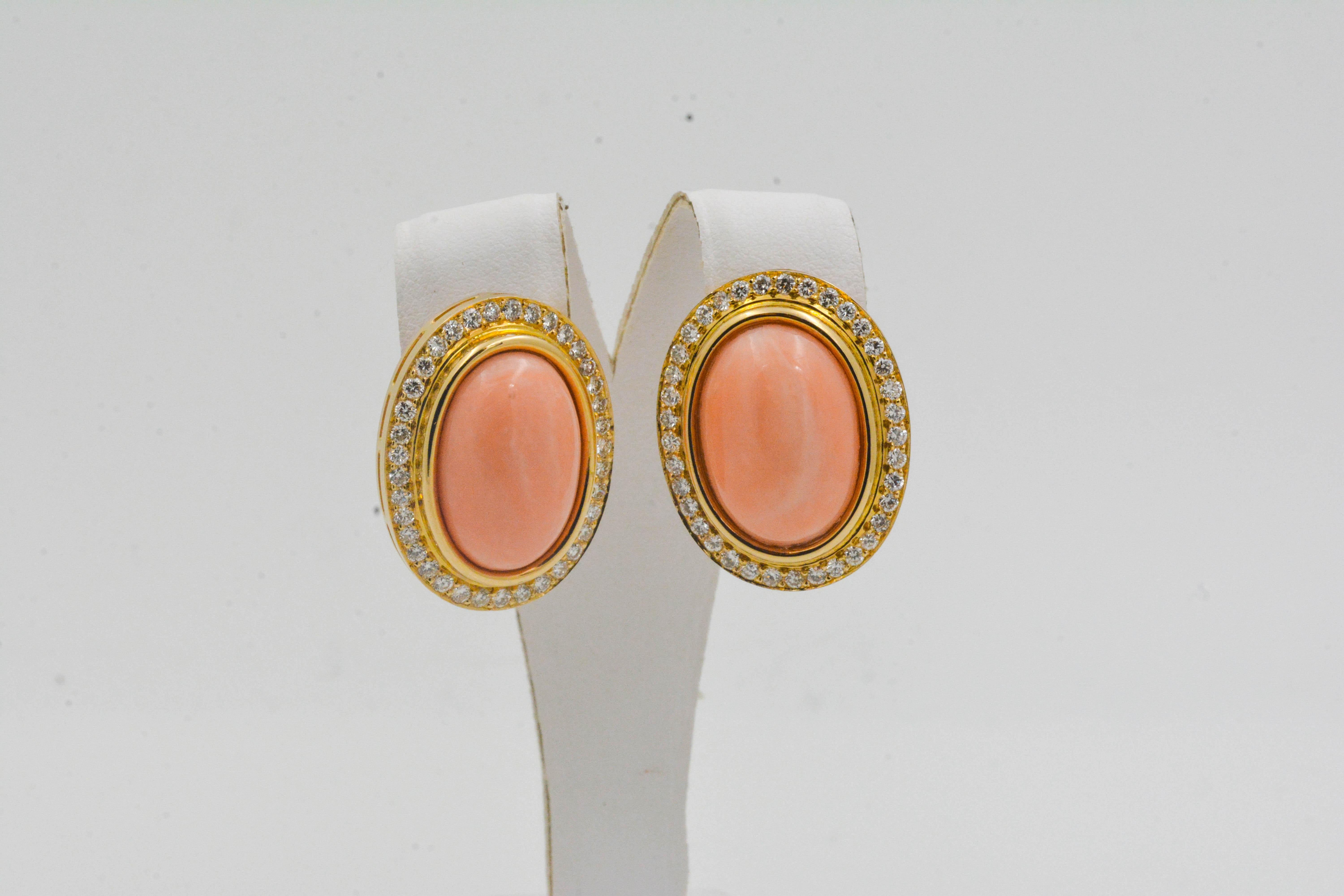 This 1980's set of 30.80 carat coral earrings are gorgeous. Two large oval coral stones are surrounded by 74 glittering round brilliant cut diamonds (1.92 carat total weight G-H color with VS clarity). These earrings are crafted in 14 karat yellow