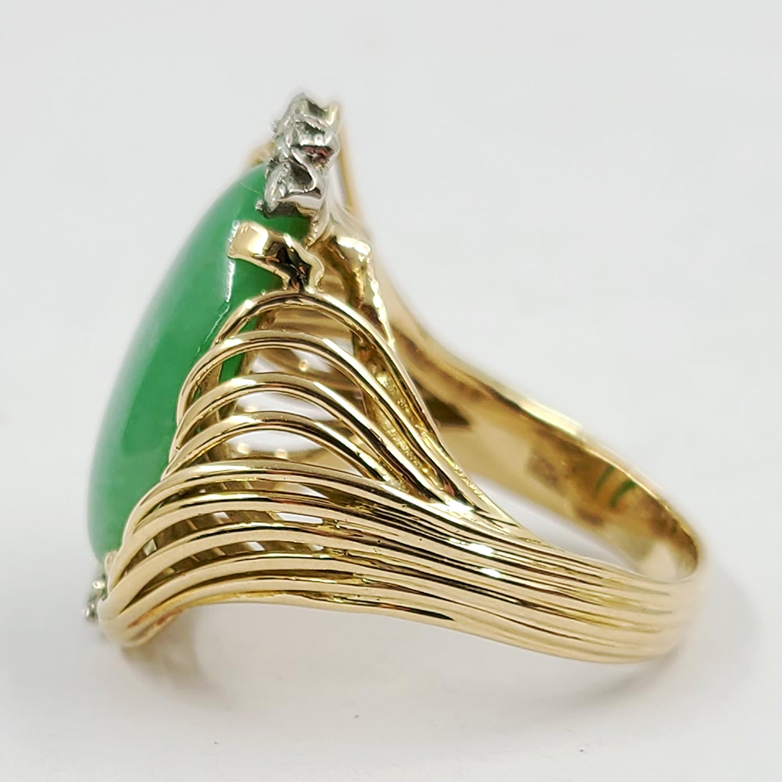 14 Karat Yellow Gold Wrapped Cocktail Ring Featuring A 19mm x 12mm Oval Jadeite Cabochon Surrounded By 7 Round Diamonds Totaling Approximately 0.15 Carats of VS Clarity & G/H Color. Current Finger Size Is 8.5; Purchase Includes One Sizing. Finished