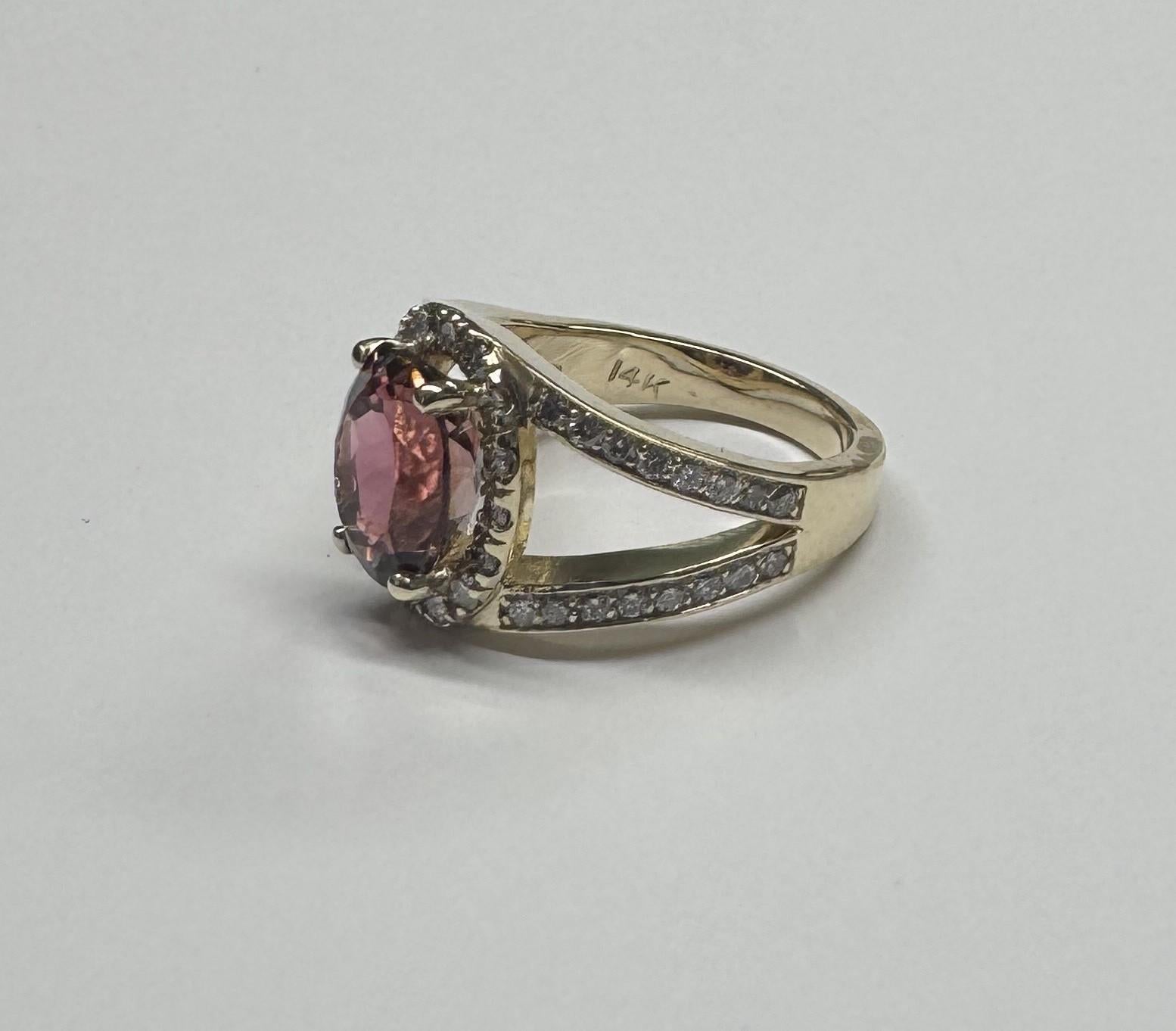 14 karat yellow gold Pink Tourmaline diamond halo ring, containing 1 oval pink tourmaline of gem quality weighing 2.95cts.  and 48 round full cut diamonds of very fine quality weighing .77pts.  This ring is a size 6 but we will size to fit for free.