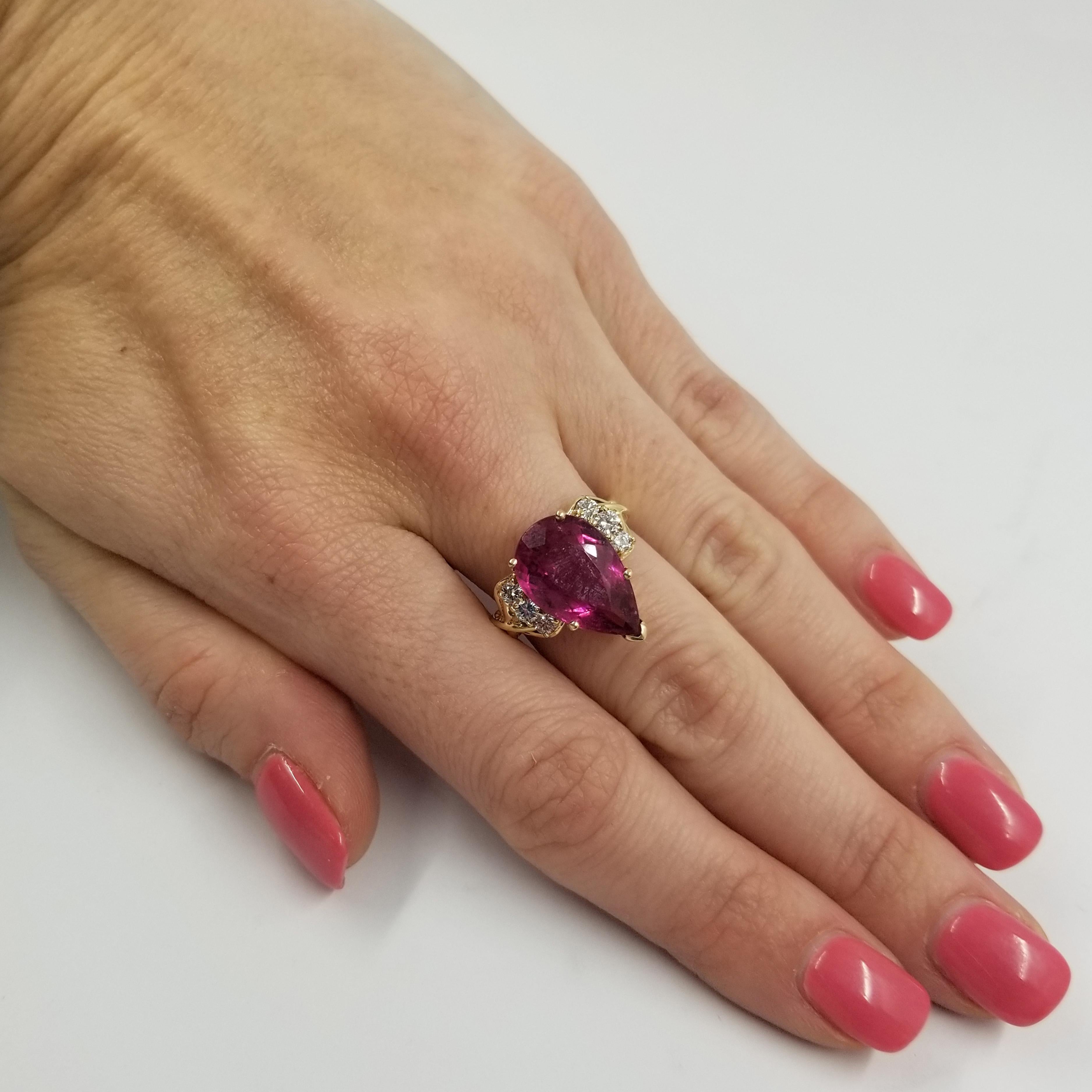 14 Karat Yellow Gold Ring Featuring A Pear Shaped Pink Tourmaline Weighing Approximately 5 Carats. It is Complimented by 6 Round Diamonds Totaling Approximately 0.25 Carat Total Weight of SI Clarity & J Color. Current Ring Size is 6.25; Your