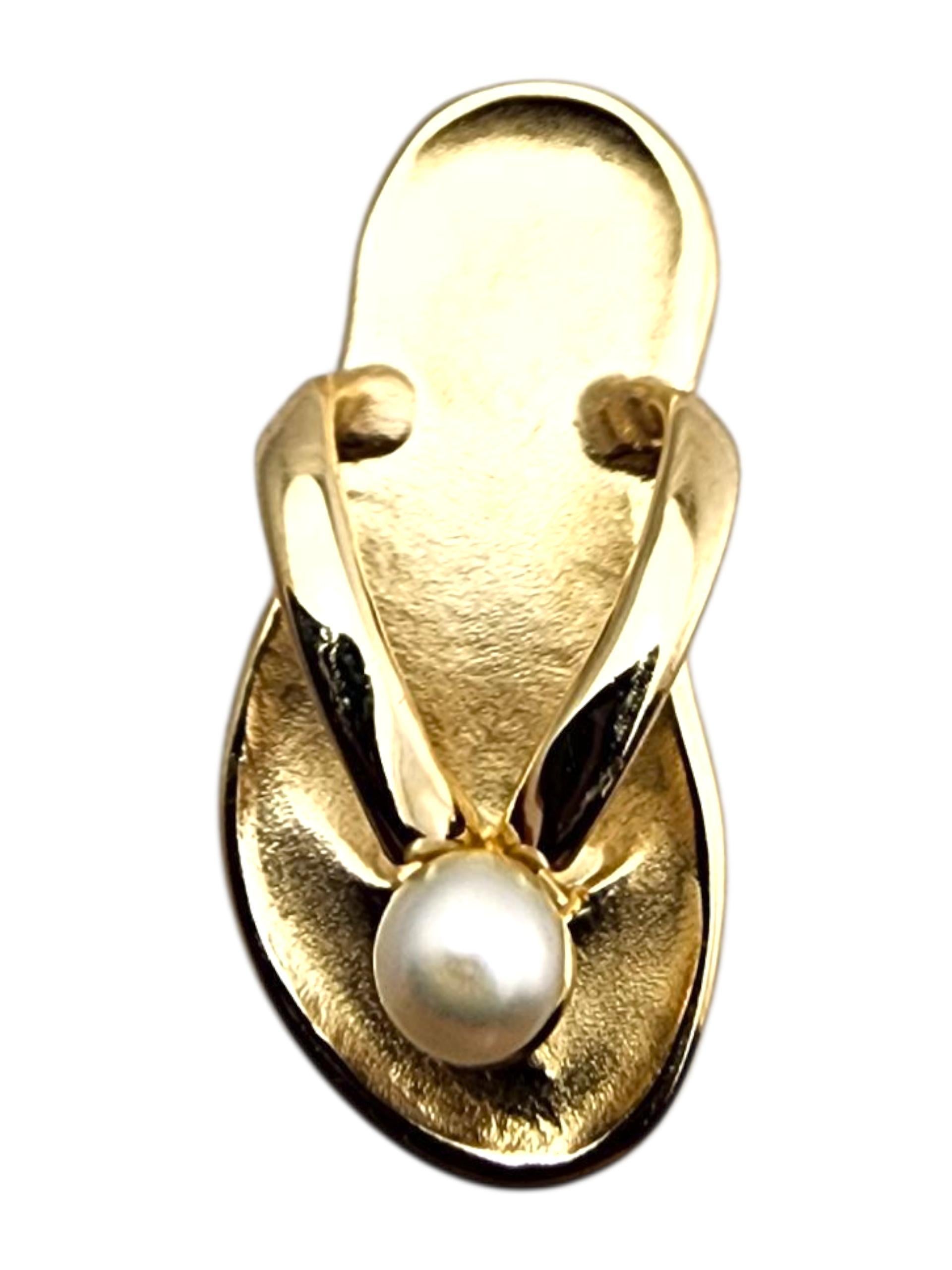 Ciondolo con perle in oro giallo 14 carati

Questo ciondolo in oro giallo 14 carati presenta un giocoso design a infradito accentato da una perla luminosa, che unisce il fascino della spiaggia a un dettaglio elegante. La sua finitura lucida aggiunge