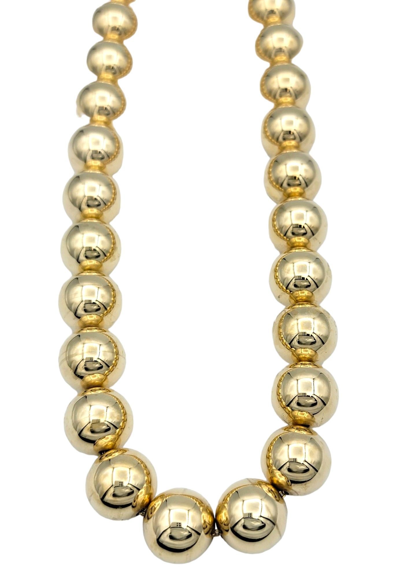This gorgeous 14 karat gold necklace boasts a stunning design featuring large ball beads crafted from high-polish gold. The spherical beads, meticulously finished to achieve a mirror-like shine, create a mesmerizing display of brilliance and