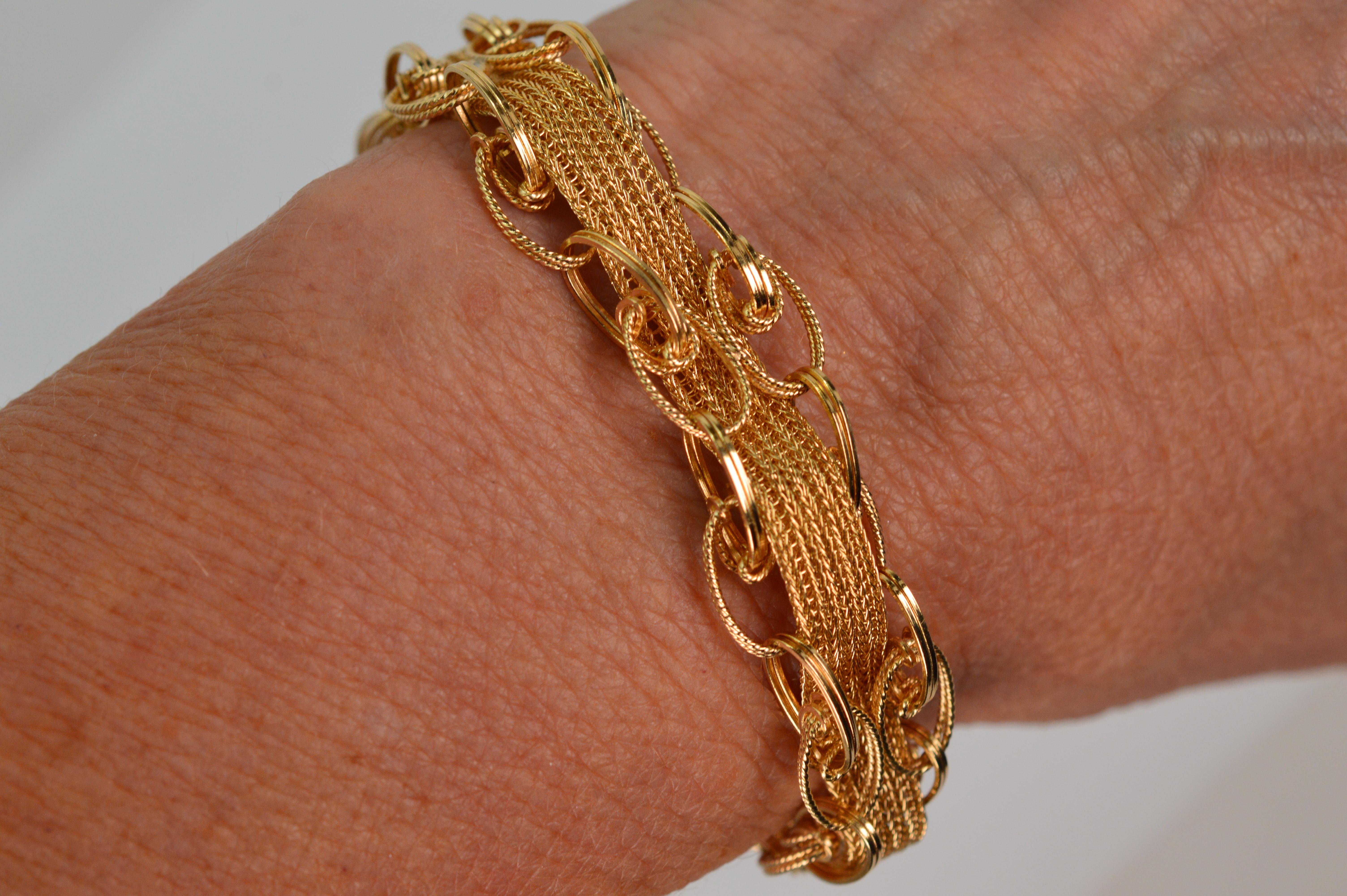 The splendor of shapes paired with textures create this alluring bracelet crafted in 14 karat yellow gold.  A four ply ribbon of 14 karat gold mesh chain with a pleasing textured finish is the foundation of this fine piece and is interwoven through