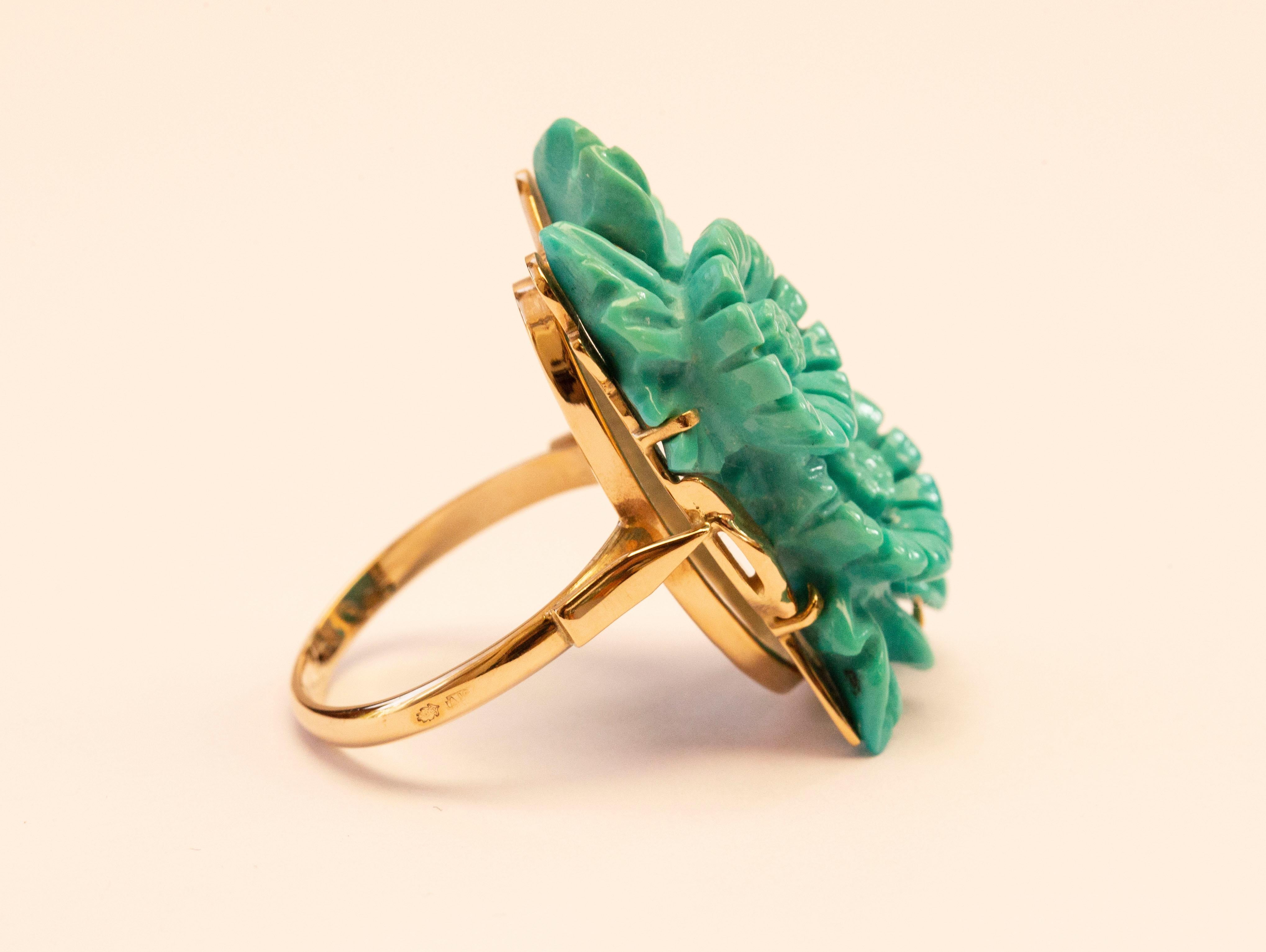 A 14 karat yellow gold ring set with turquoise carved om floral decor. The ring features an impressive color as well as size and it is definitely an eye catcher. It was manufactured in the 1970s. 
Despite its age the ring is still in a really good