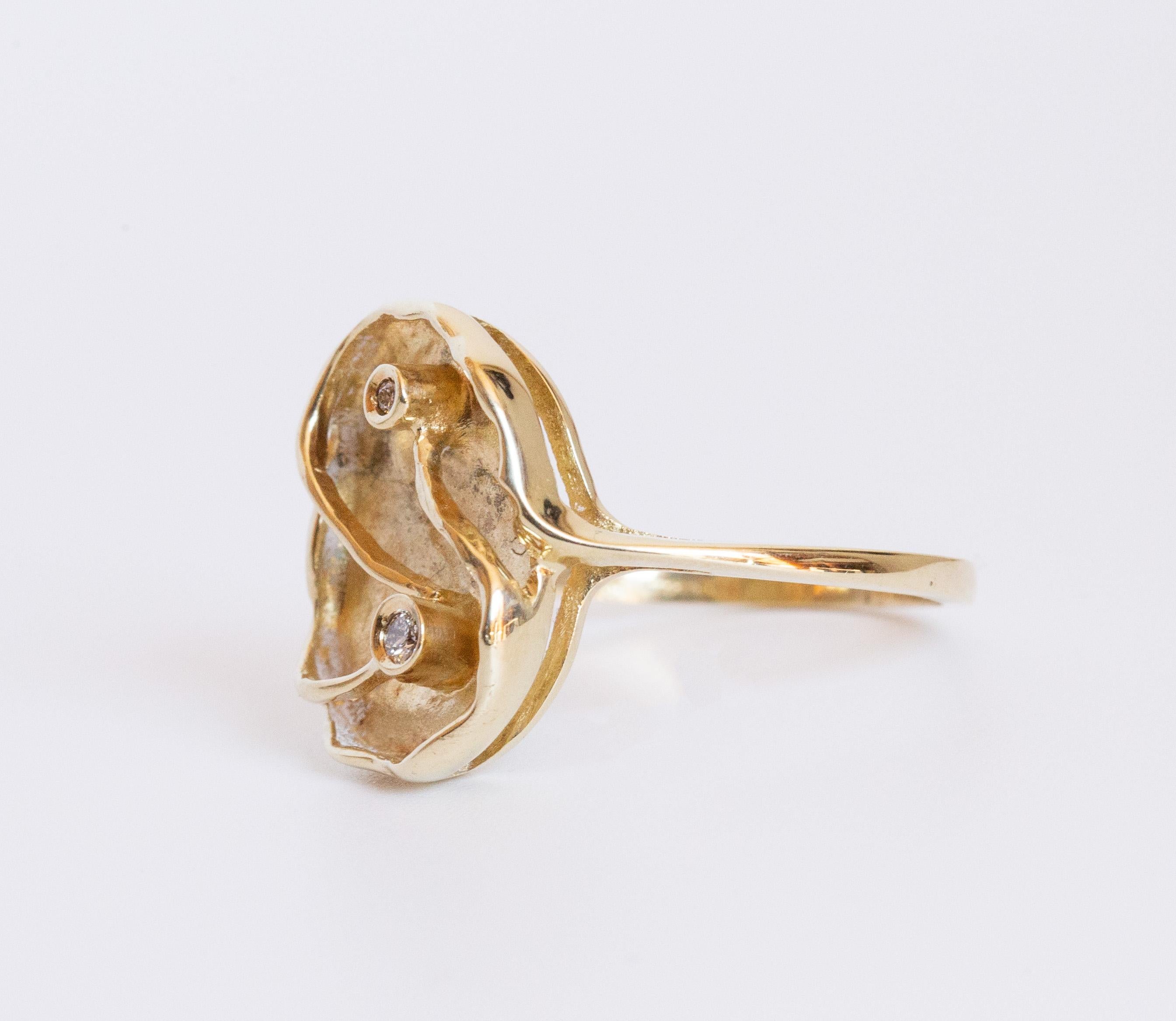 Bague moderne en or jaune 14 carats avec diamants. Le centre de la bague présente un design asymétrique et partiellement mat et est serti de deux diamants de taille brillant. 
L'intérieur de la bague est marqué de 585, ce qui signifie 14 carats