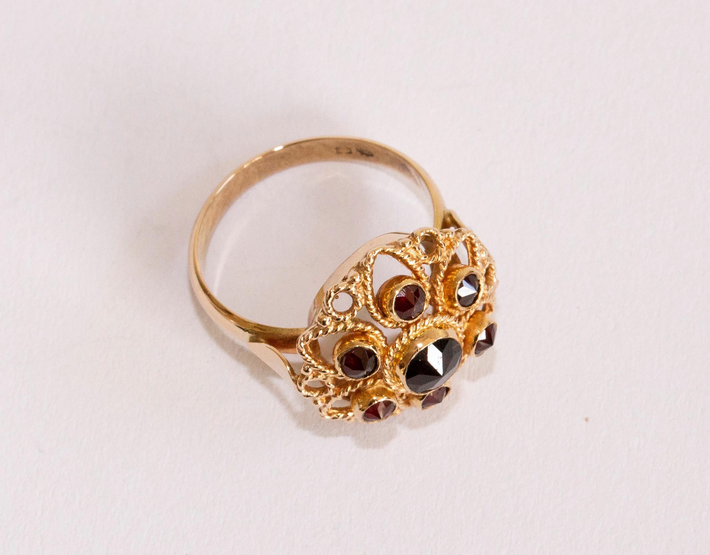 A 14 karat yellow gold rosette ring with garnet. The ring is set with 7 faceted garnets in filigree flower setting made of cord frame. The ring is stamped with 585 that stands for the 14 karat gold content. It was also acid tested for the gold