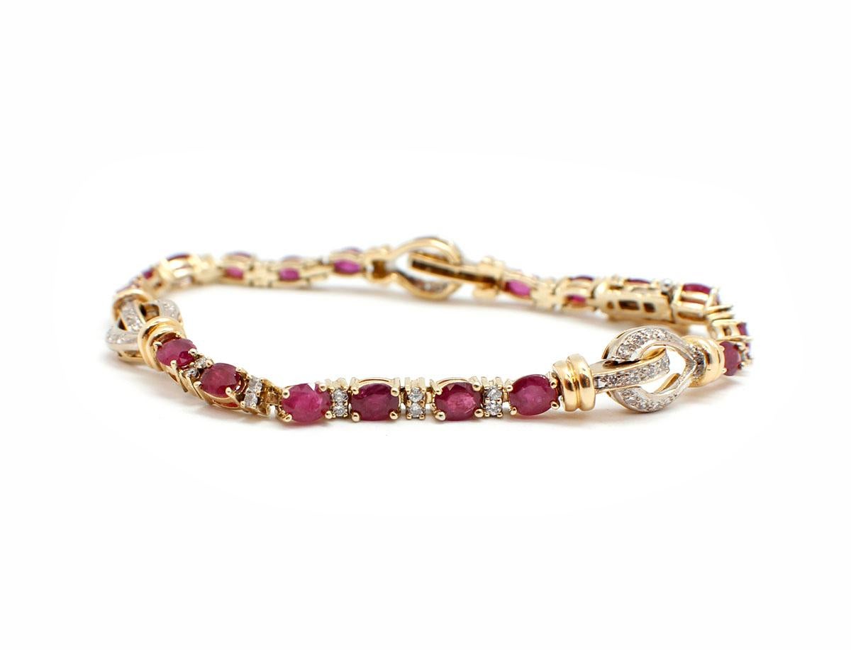 This bracelet is made in 14k yellow gold, and it features 18 oval-cut rubies with a total weight of 5.40cts. There are 69 round diamond melee set in links accenting. There are three stirrup style links set with diamonds also. The diamonds have a
