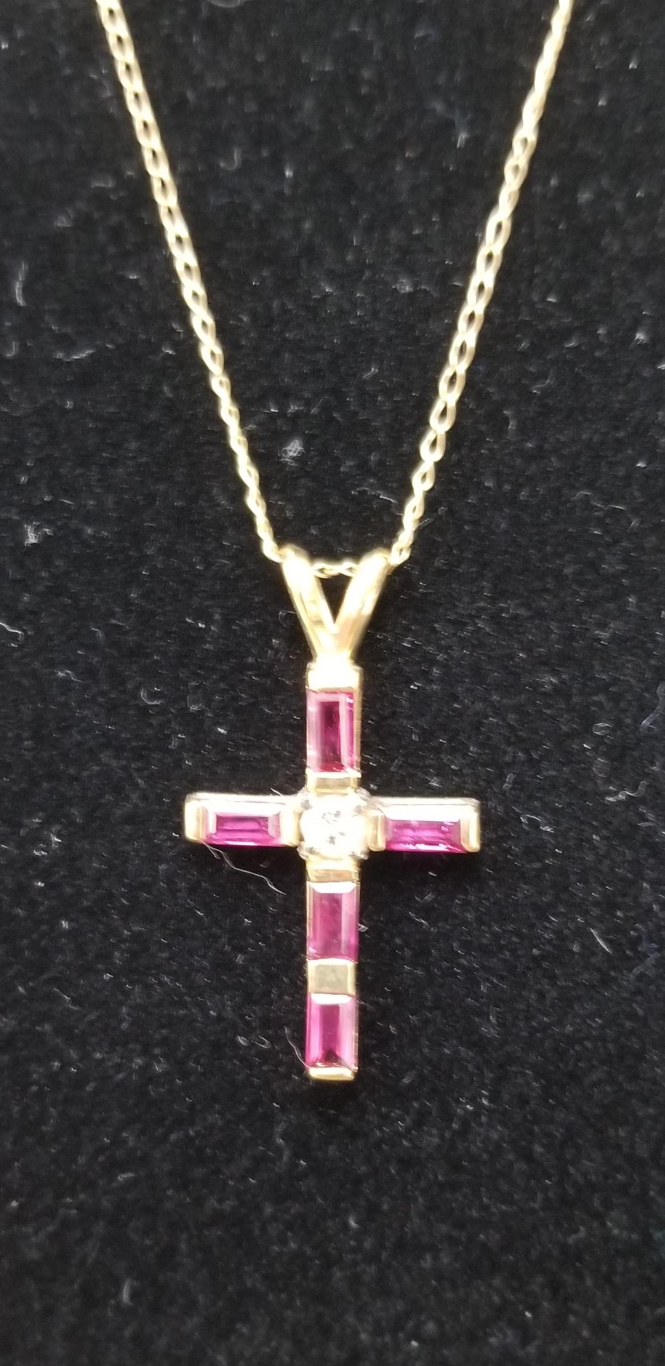 14k yellow gold 4 baguette rubies weighing .60pts. and 1 round full cut diamond weighing .09pts. on a 18 inch small link chain.