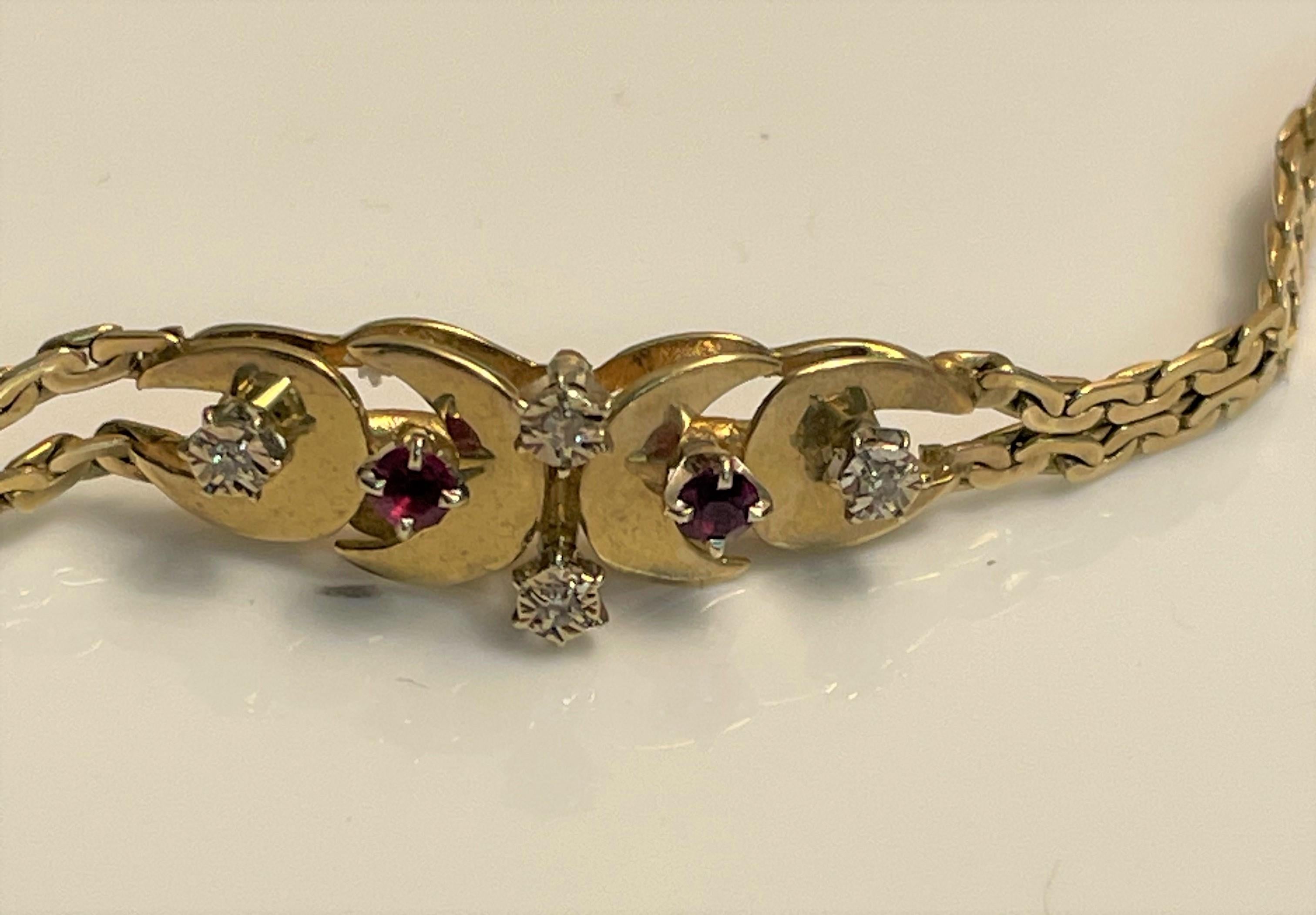 This simple beautiful bracelet is a staple that can be worn daily.  
14 karat yellow gold double serpentine chain
Four round diamonds and two round rubies, prong set
Center detail resembles four half moons, each adorned with either a diamond or a