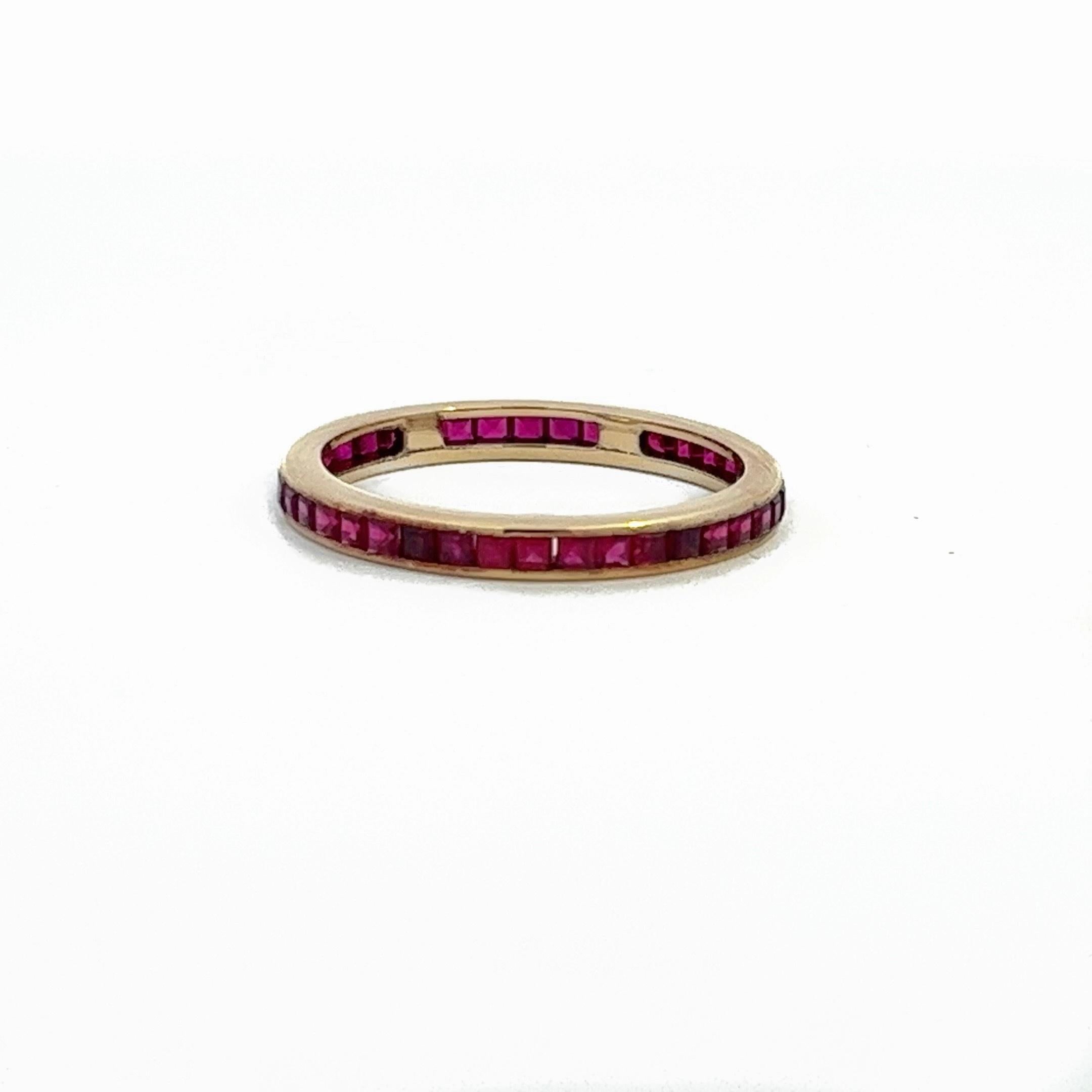 This is a dainty and elegant French cut Ruby eternity band crafted in 14 karat yellow gold. The band features 40 rubies showcasing hues of burgundy, pink, and red. The combination of the precious gemstones and gold creates a captivating and