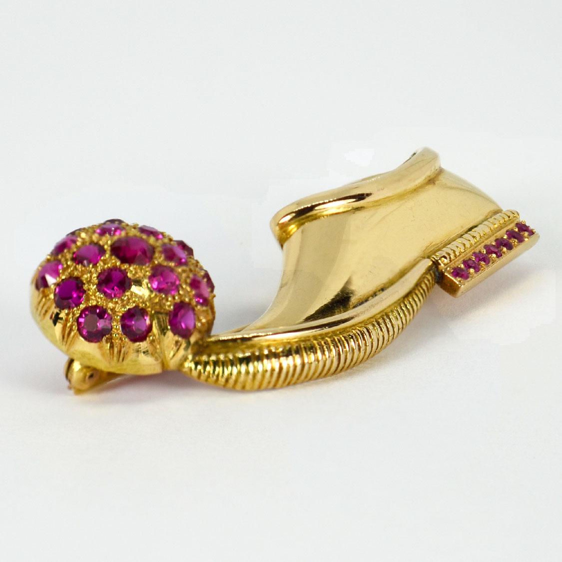 A 14 karat yellow gold brooch designed as a Greek tsarouchi shoe decorated with synthetic rubies to the heel with a ruby studded ball balanced on the toe. In the style of Vourakis and Paul Flato. Unmarked but tested as 14 karat gold.

Dimensions: 5