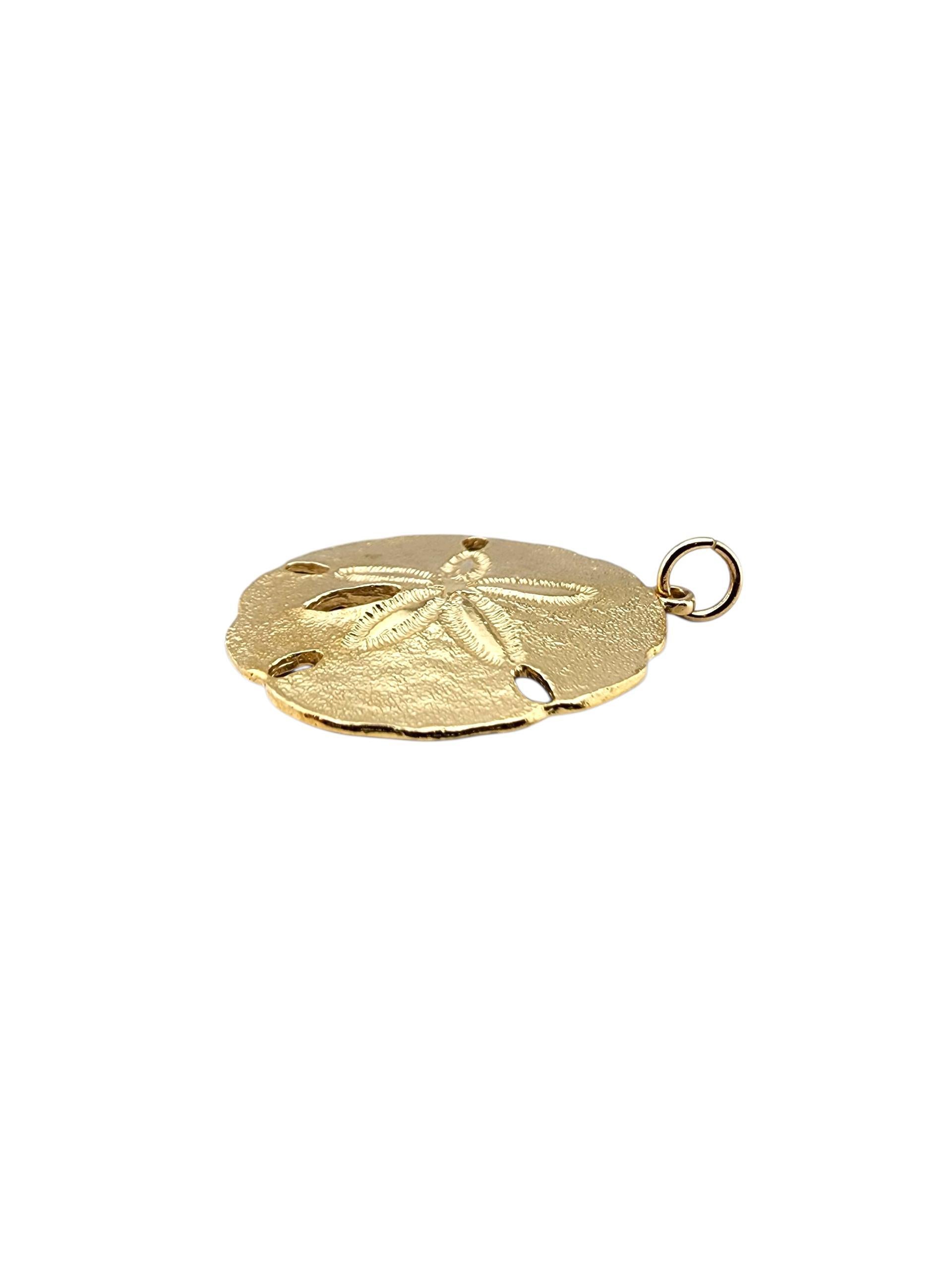 Ciondolo a forma di dollaro di sabbia in oro giallo 14k

Questo ciondolo a forma di dollaro di sabbia in oro giallo 14 carati cattura il fascino della costa con i suoi dettagli strutturati, un pezzo brillante che porta un tocco di mare al tuo