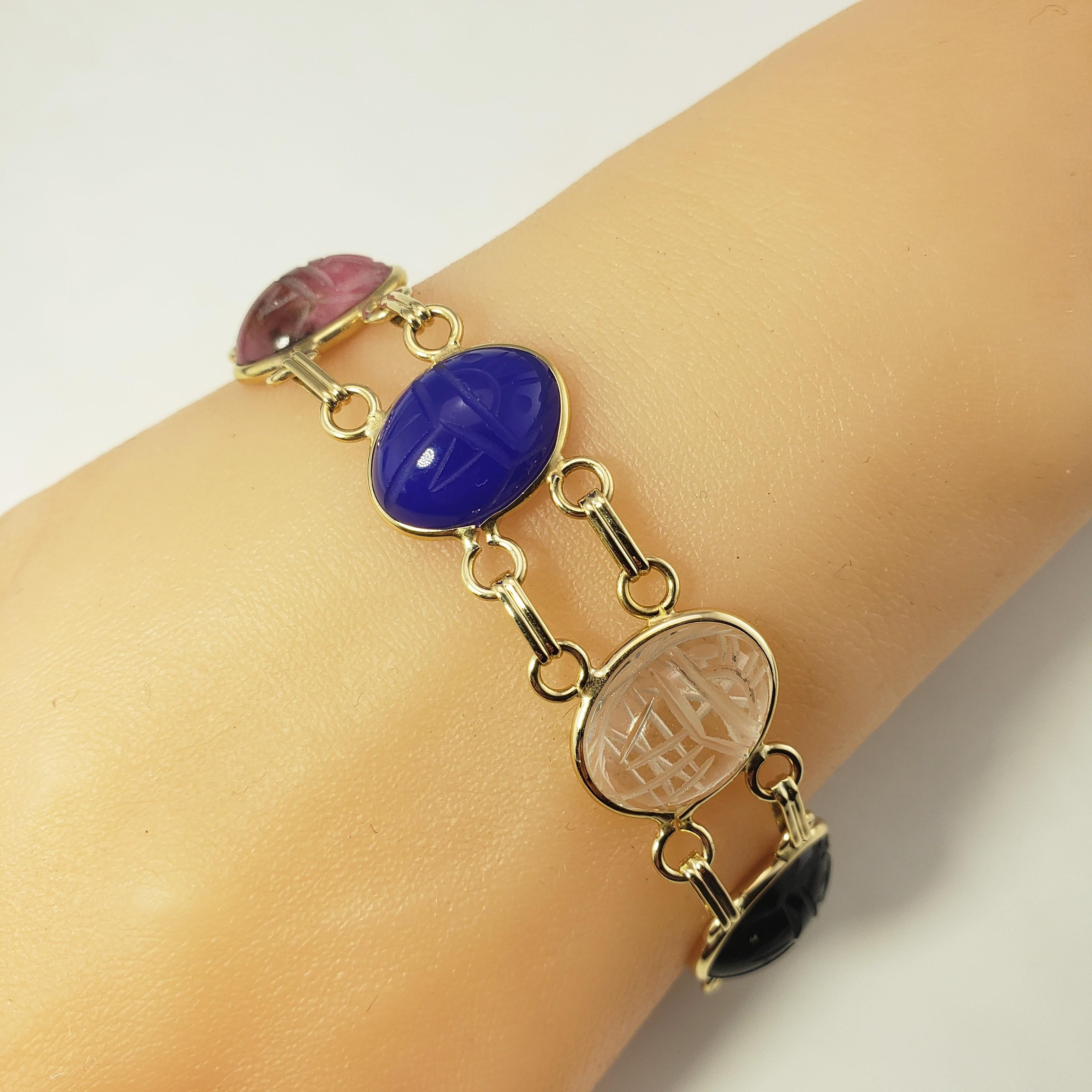 By Vintage 14 Karat Yellow Gold Scarab Bracelet-

Ce charmant bracelet scarabée est composé d'onyx, de jade, de quartz, de lapis-lazuli, de corail et d'œil de tigre, le tout serti dans de l'or jaune 14 carats.
Chaque pierre mesure 16 mm x 12