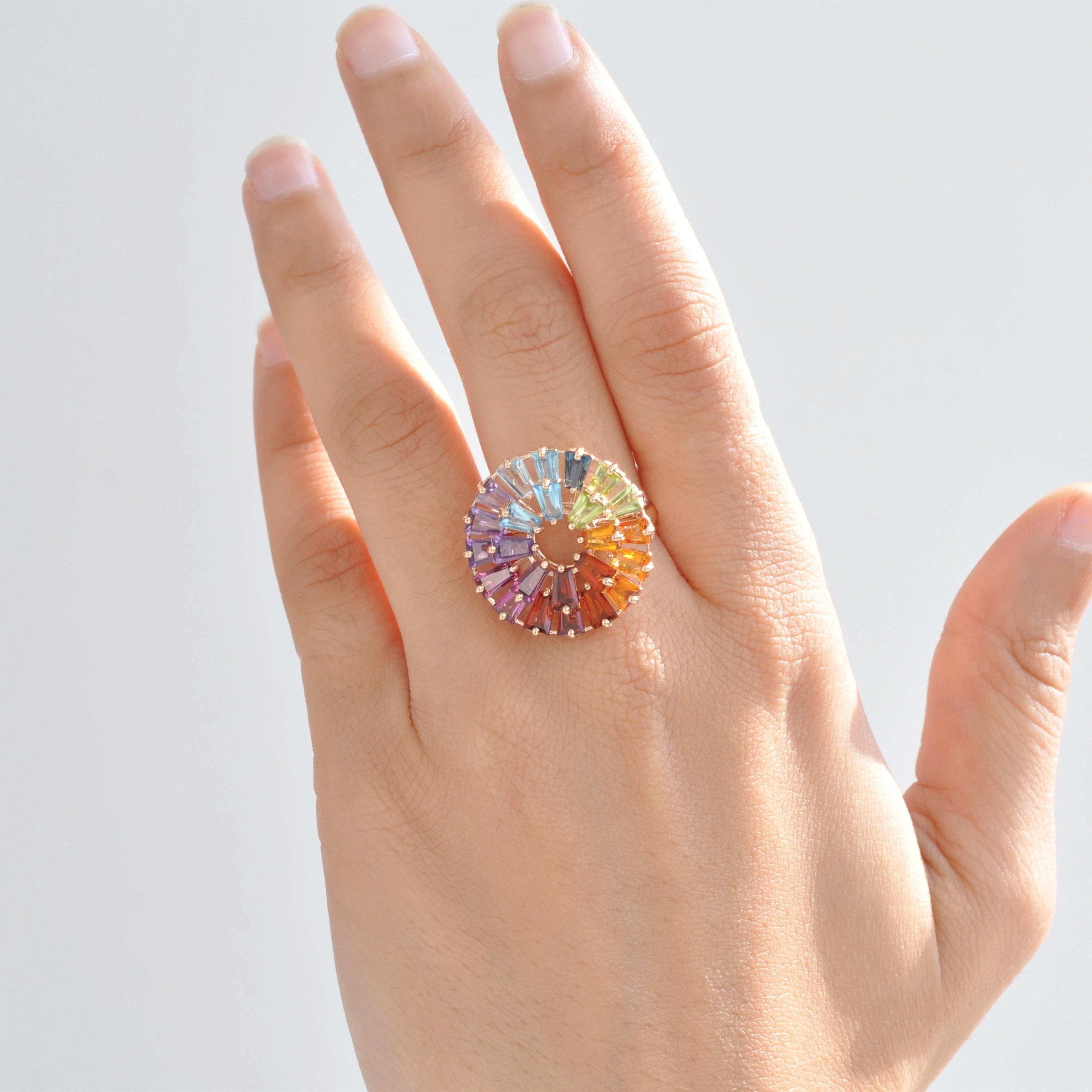 This striking ring is crafted in 14-karat yellow gold and adorned with a vibrant selection of multicolor gemstones, exuding elegance and a playful charm. The ring features 24 tapered baguette-cut gemstones, each measuring 5mm in length, in a
