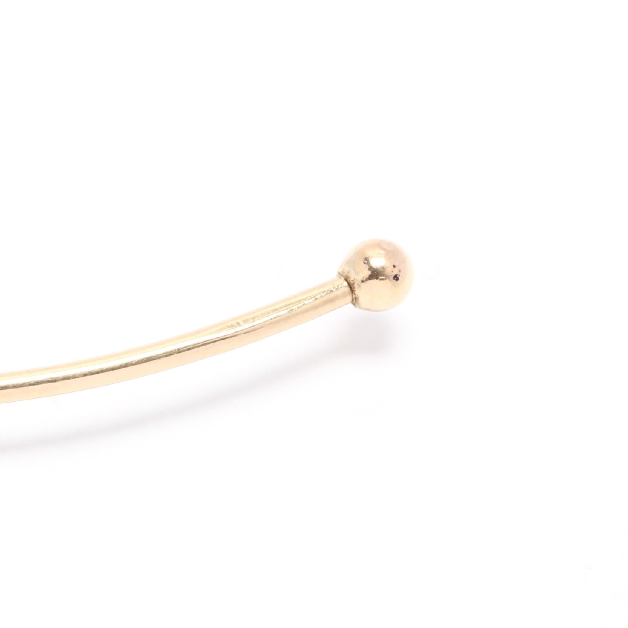 A 14 karat yellow gold thin flexible choker necklace. This necklace features a round, thin design that is flexible and can twist back and forth, as well as pull slightly apart so that it can slide on to the neck easier. It is completed with a gold