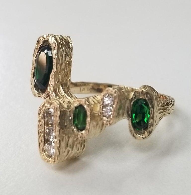 k yellow gold tsavorite and diamond ring, containing 3 oval cut  tsavorite weighing 1.31cts. and 5 round full cut diamonds of very fine quality weighing .55pts.  Set in a free form nugget ring.  This ring is a size 7 but we will size to fit for