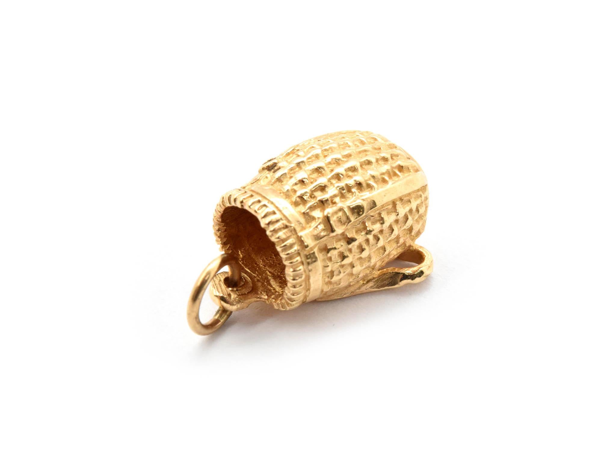 This charm is made in 14k yellow gold in the shape of a basket on a stand. The charm measures 12x17mm, and it weighs 4.7 grams.