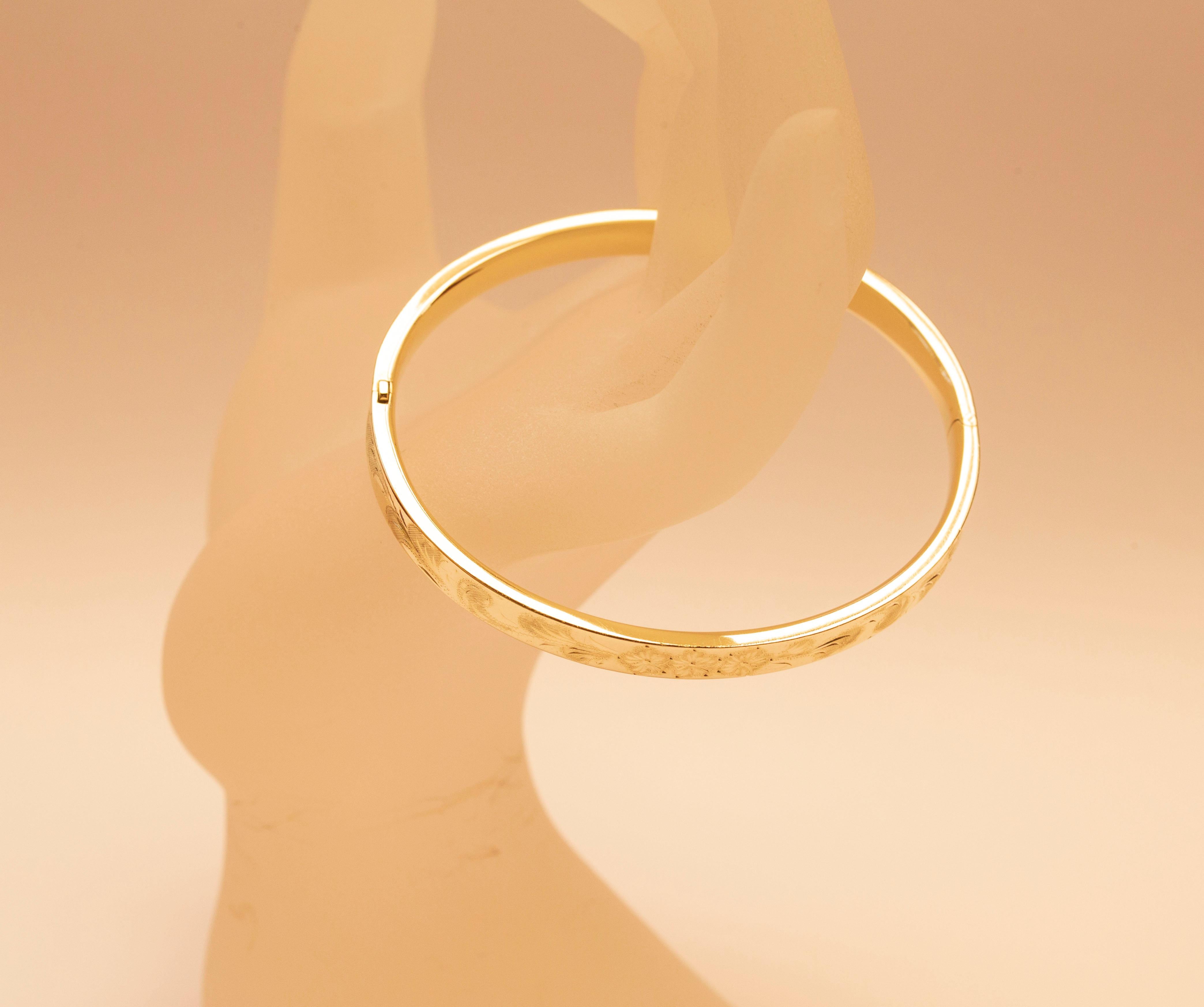 A vintage 14 karat solid yellow gold bangle bracelet with engraved floral and leaf decoration. The bracelet was made in the 1960s. The item features a retro vibe that can be matched with classy as well as modern outfits. The bracelet is in very good