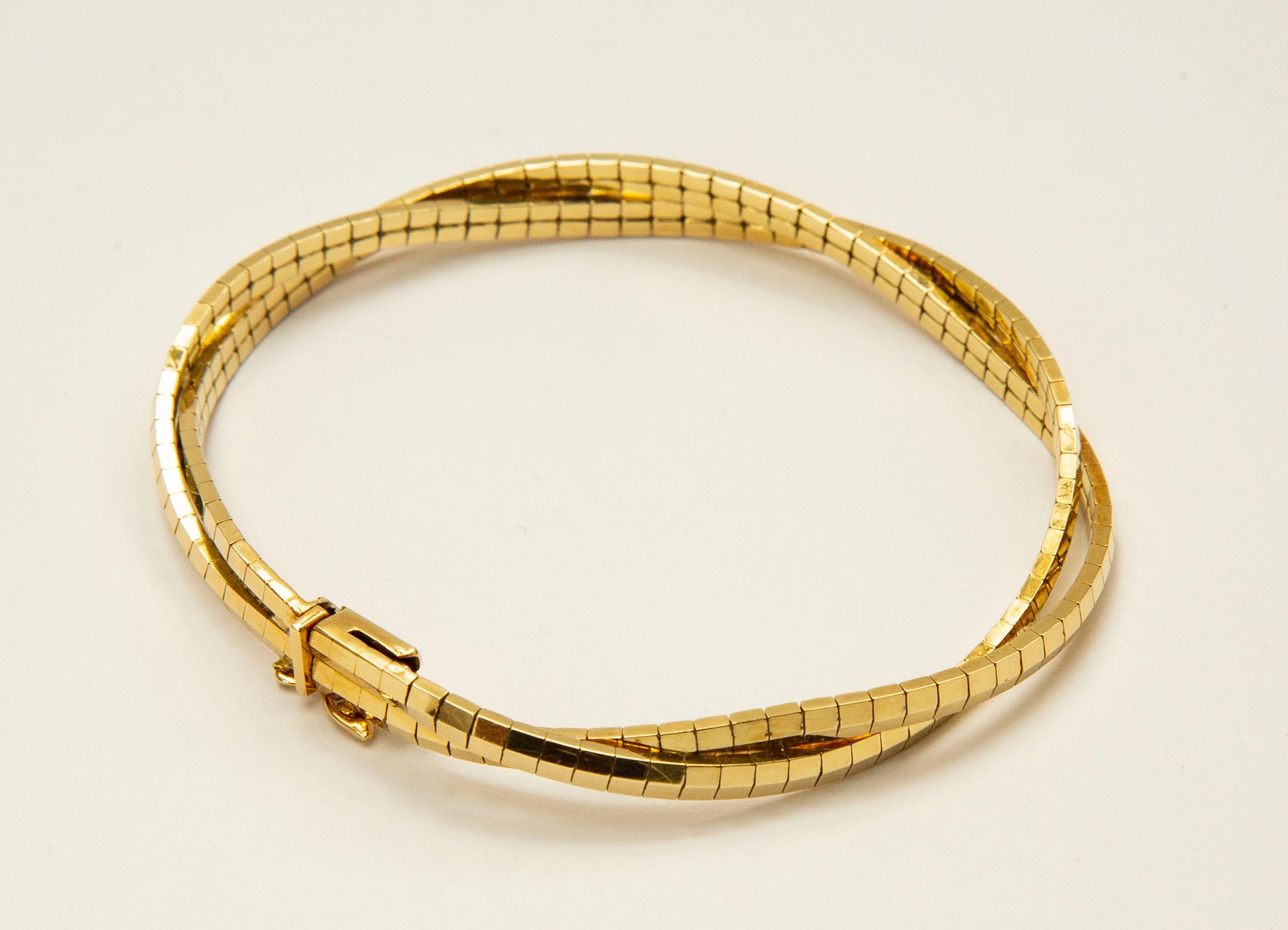 A vintage 14 karat yellow solid gold bracelet (ca. 1970s-1980s). The bracelet features golden bars in two twisted rows. It is semi flexible ant it closes with  a box clasp and safety figure eight lock. 
The bracelet has modern and quite simple
