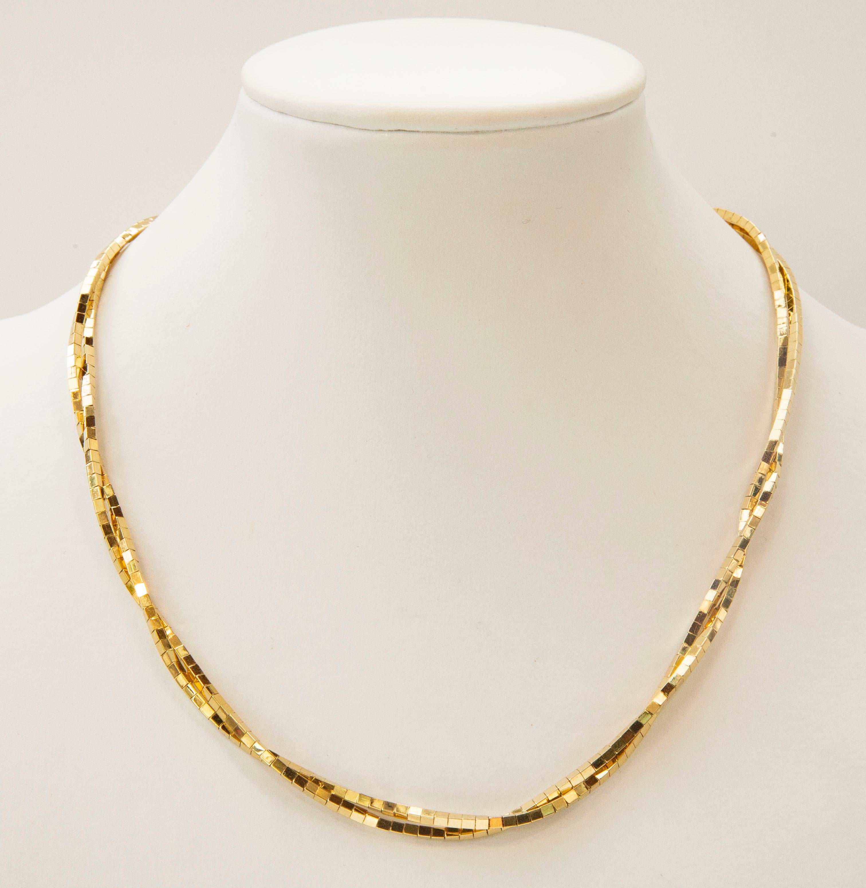 A vintage 14 karat solid yellow gold necklace. The necklace features golden bars in two twisted rows. The gold is shiny and has a moderate color of gold (i.e. not very vivid and dark gold color).  The style of the necklace is modern and quite