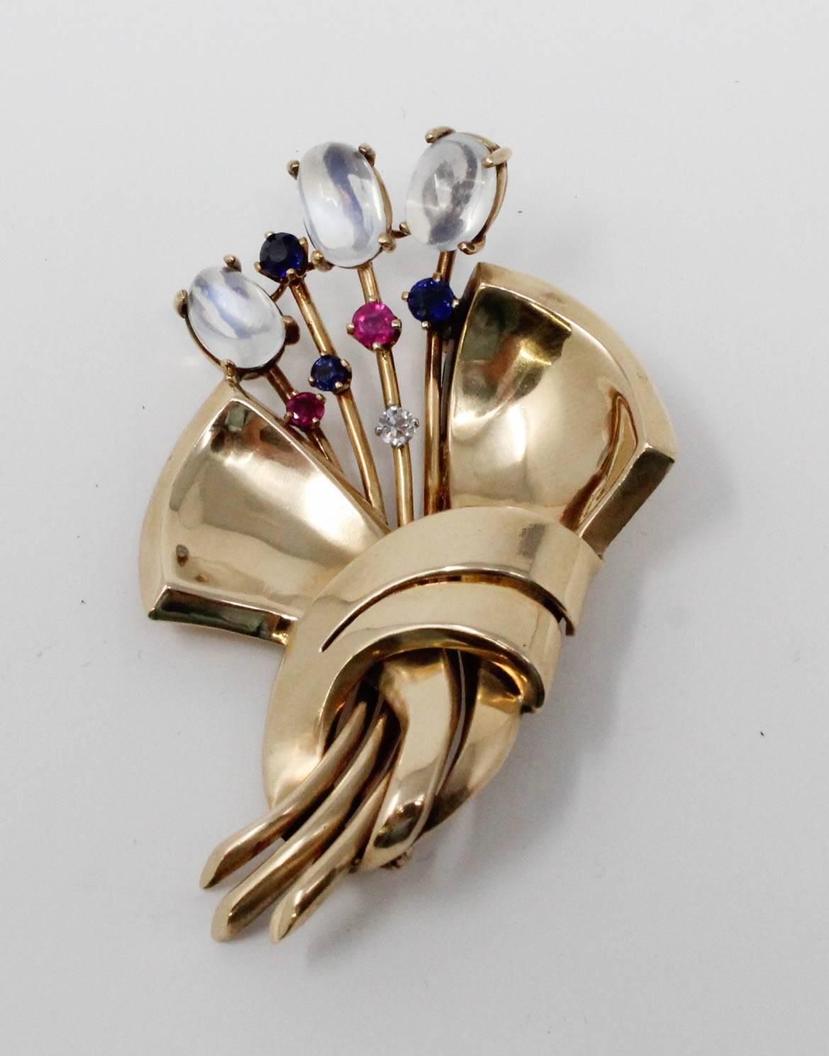 1940's Retro brooch of fourteen karat yellow gold with gemstones. There are a total of three moonstones, three sapphires, two rubies and a single diamond.