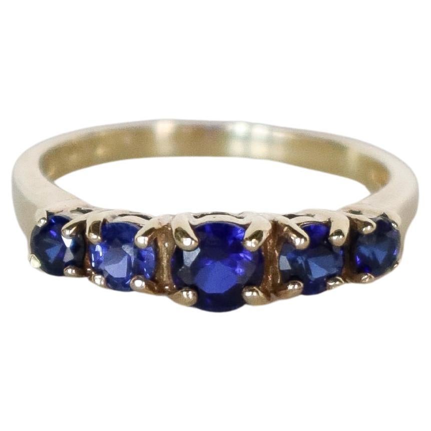 Discover the elegance of this vintage 14k gold ring, featuring five exquisite round cut dark blue sapphires. Each gemstone is expertly set in polished gold, creating a striking piece that exudes sophistication and timeless style. The dark blue color