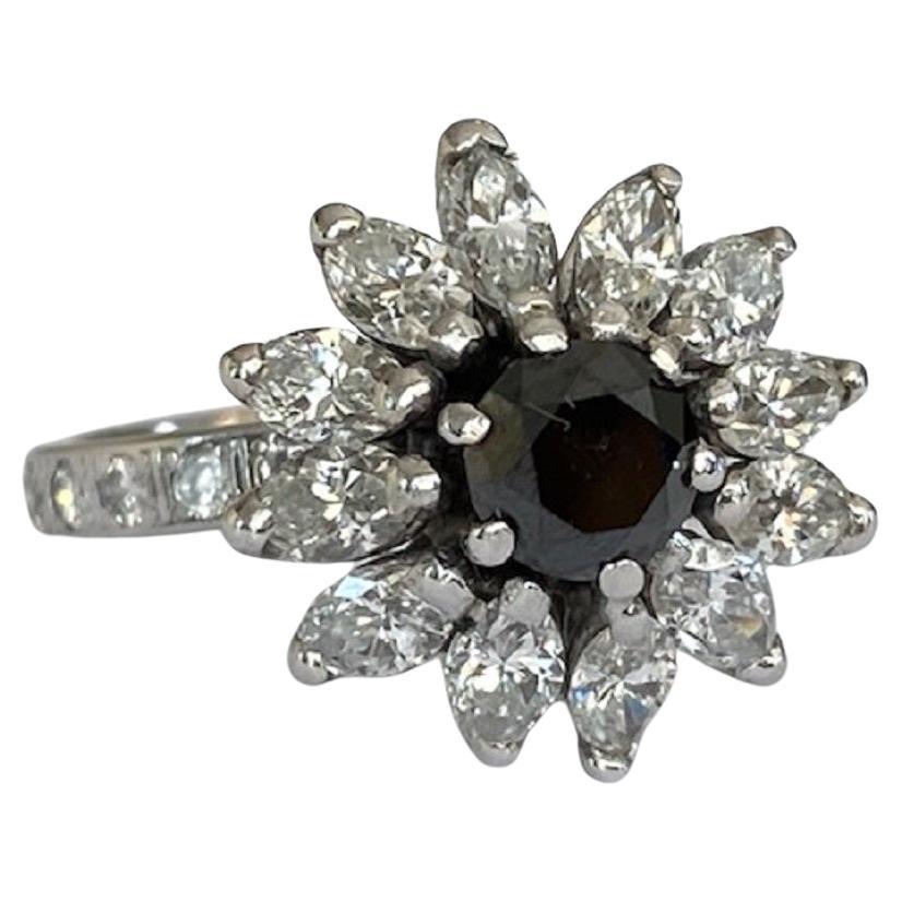 Offered in good condition, vintage 14 kt white gold entourage designer  ring with 25 pieces of brilliant cut diamonds of approximately 0.50 crt H/VS/SI and in the middle of 1 piece of black diamond of approximately 1.00 crt, surrounded by 12 pieces