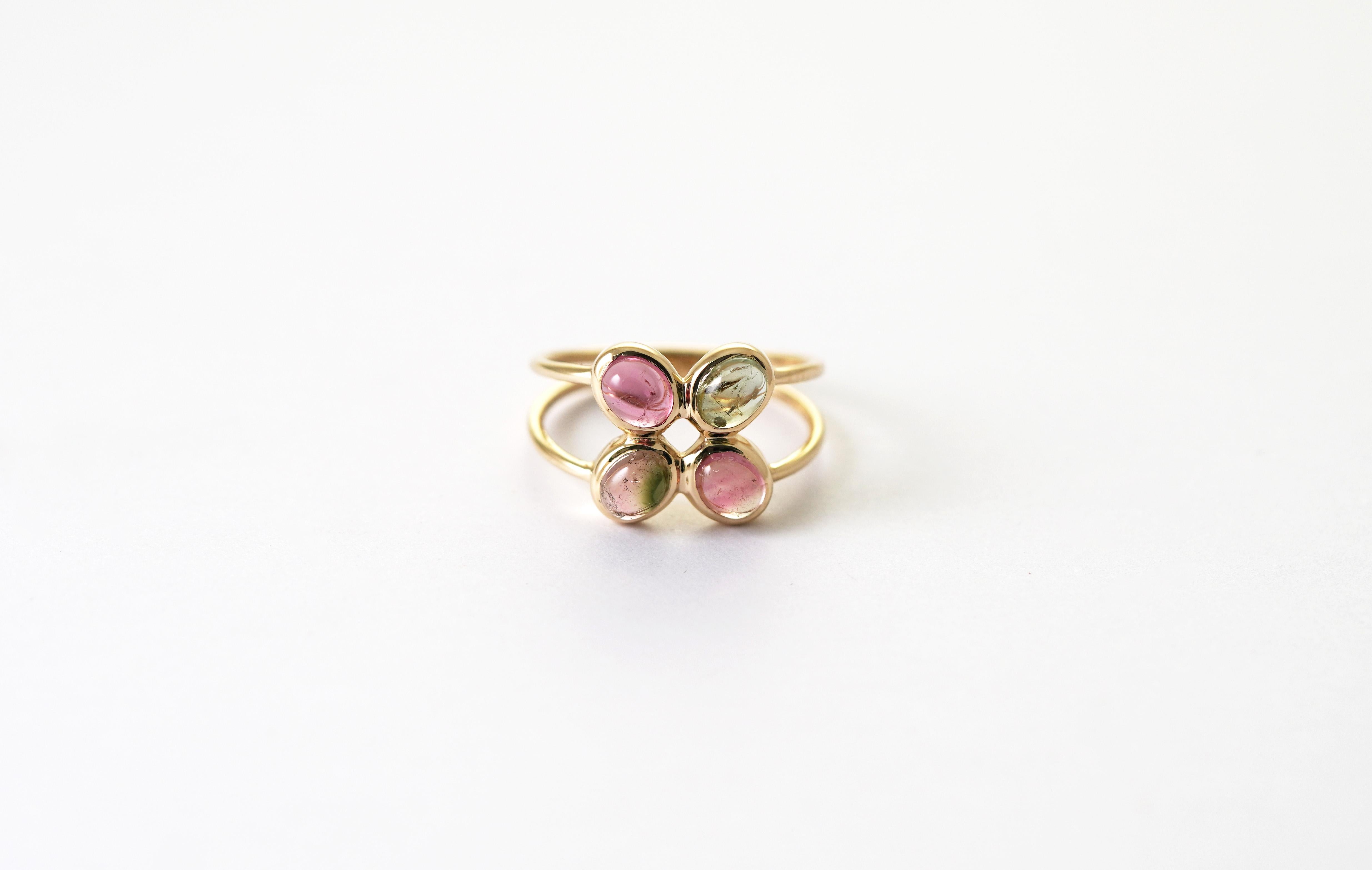 Cette bague en or jaune 14 kt, à la fois délicate et artistique, met en valeur quatre cabochons de tourmaline multicolore, disposés en forme de trèfle qui attire le regard sous tous les angles. Chaque pierre précieuse présente son propre dégradé