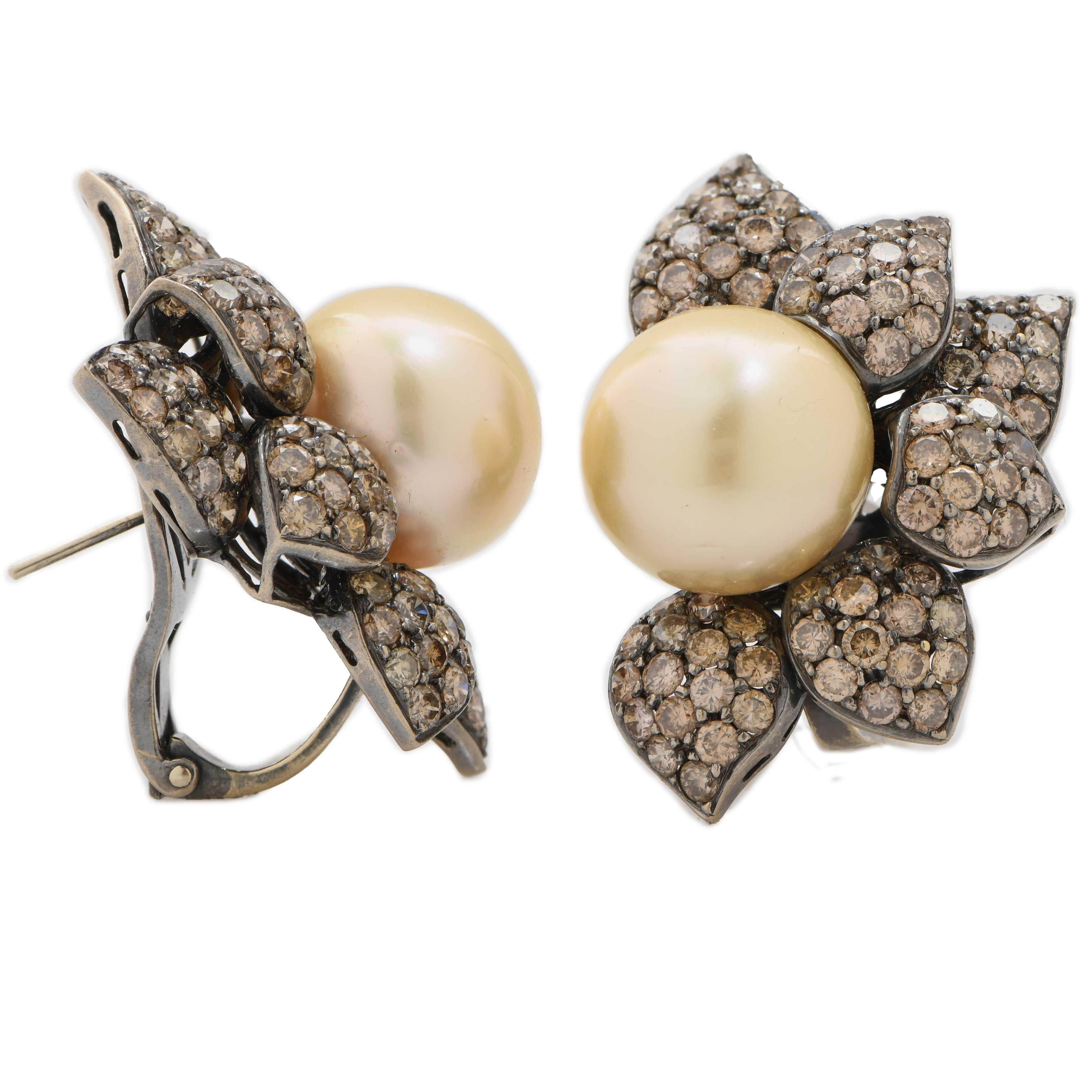 A captivating pair of 18-karat white gold earrings exquisitely crafted in a refined flower motif, blending elegance with bold sophistication. Each earring features a luminous 14mm golden South Sea pearl at its center — celebrated for its exceptional
