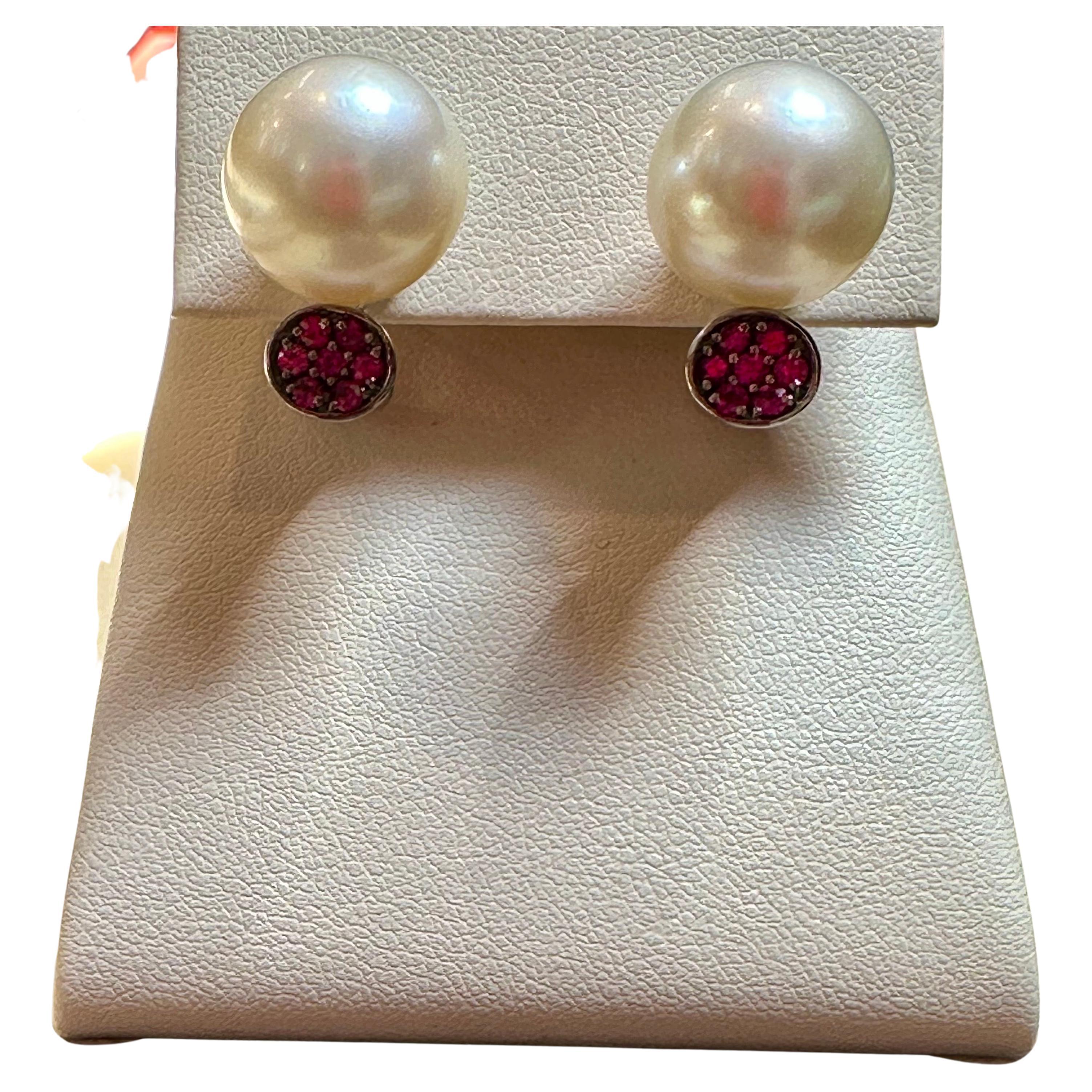 Presenting the exquisite 14mm Round South Sea Pearl & Ruby Cocktail Stud Earrings, a magnificent estate piece. These captivating earrings are crafted from 18 Karat white gold, showcasing a timeless beauty. 

Each earring features a lustrous South