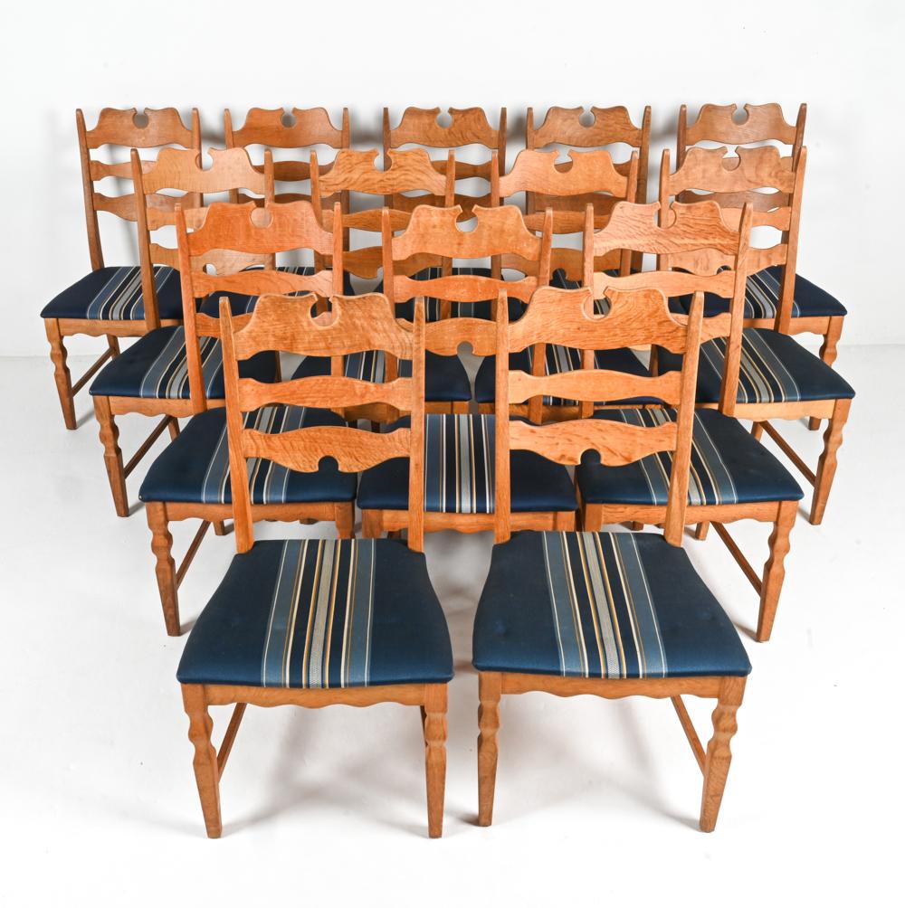 Perfect for the design aficionados, this is a rare, large set of 14 Danish dining chairs, crafted from rich, warm oak designed by the famous Henry 'Henning'  Kjaernulf. These chairs are made in the iconic 